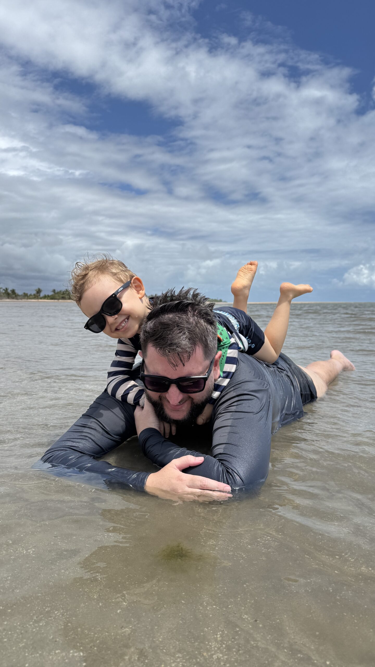 Rudi brincando com Samuel na água rasa de uma praia de Maceió