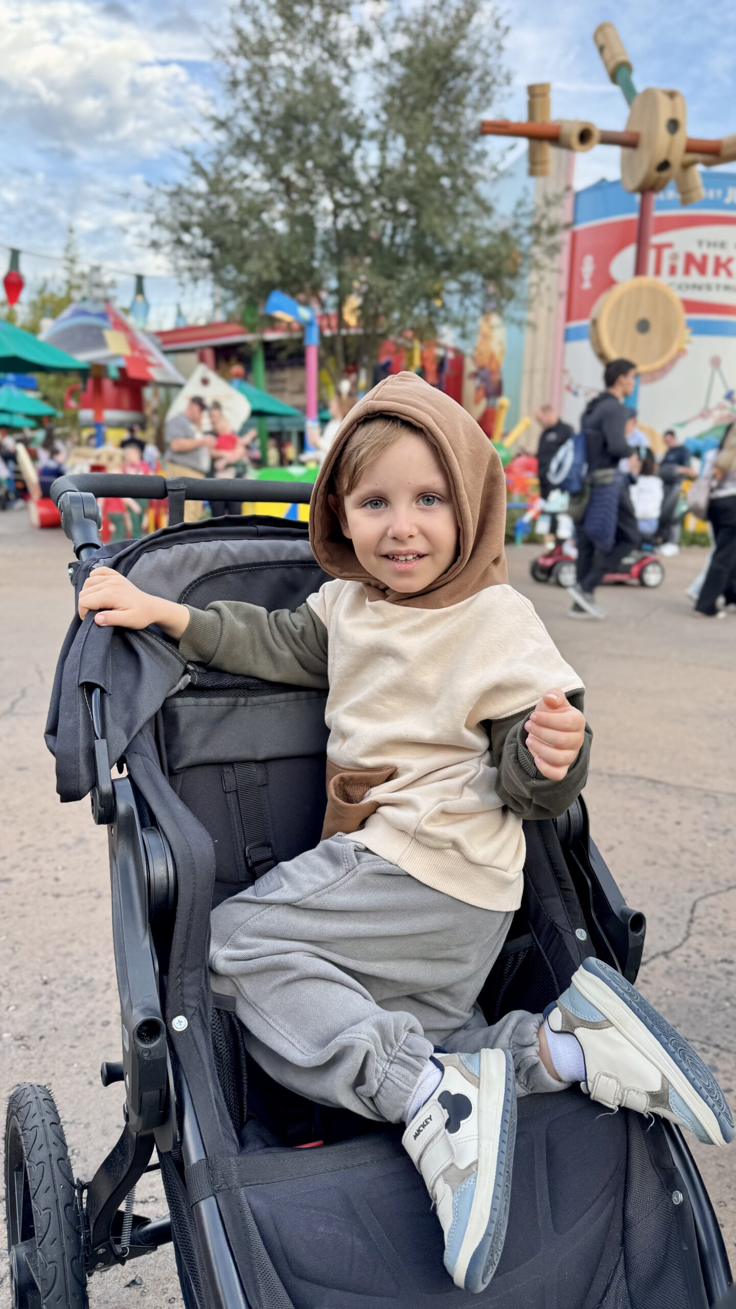Sam no carrinho em Toy Story Land com a ambientação colorida ao fundo