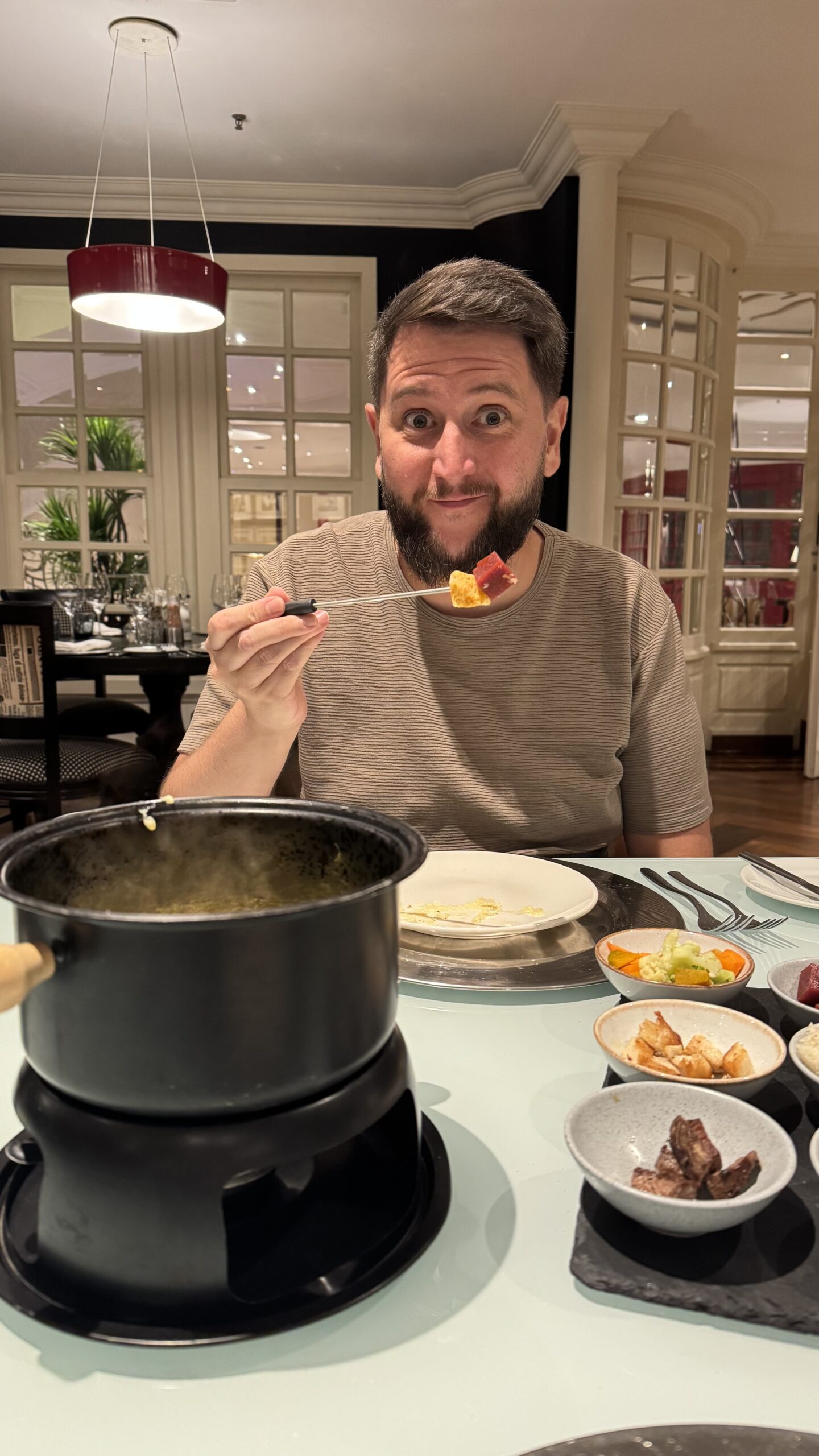 Rudi mergulhando no fondue de queijo do Grand Mercure Ibirapuera durante a Experiência Nível 1 da ALL Accor