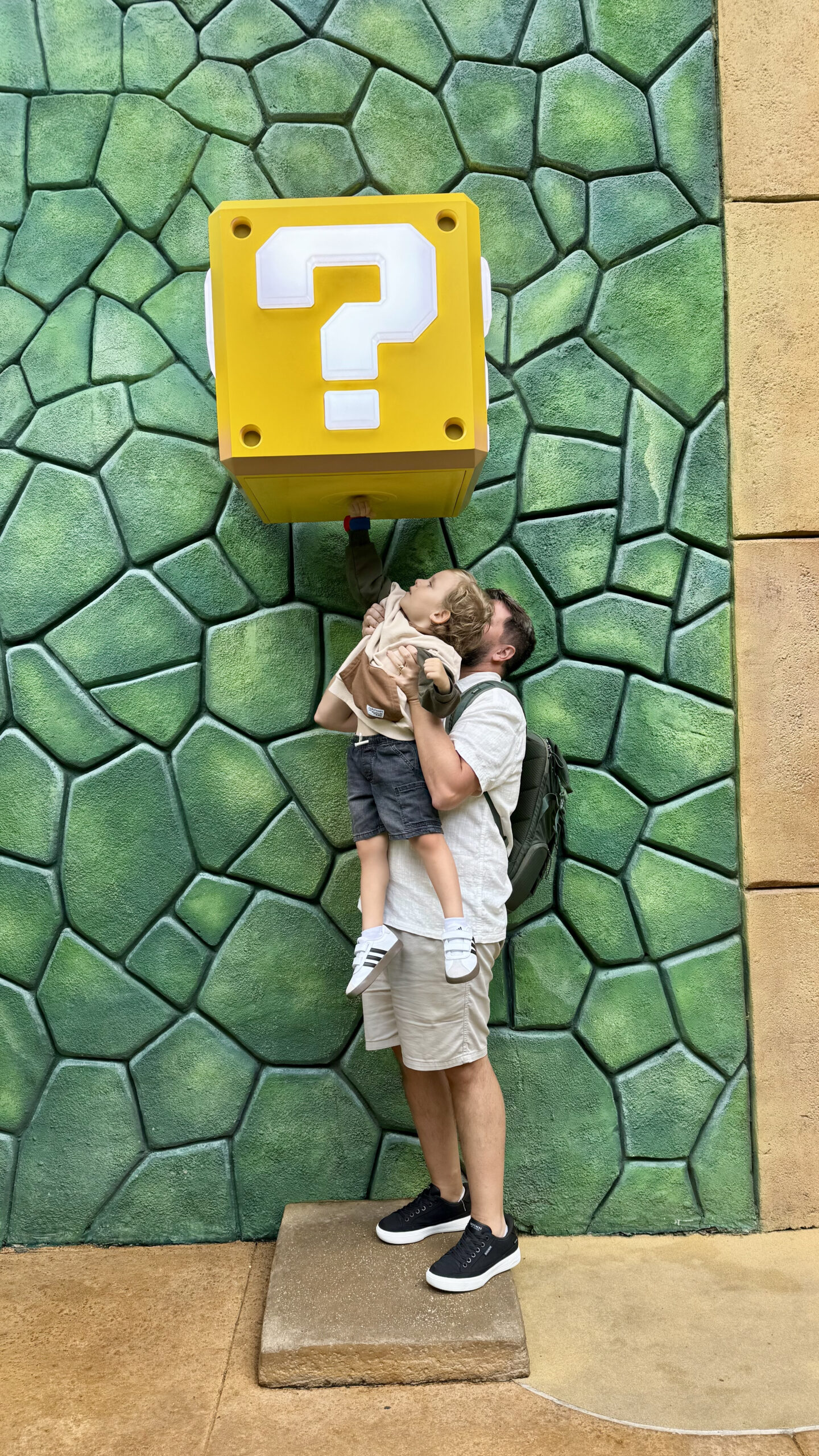 Rudi segurando Sam para tocar o bloco de interrogação no Super Nintendo World do Epic Universe Orlando