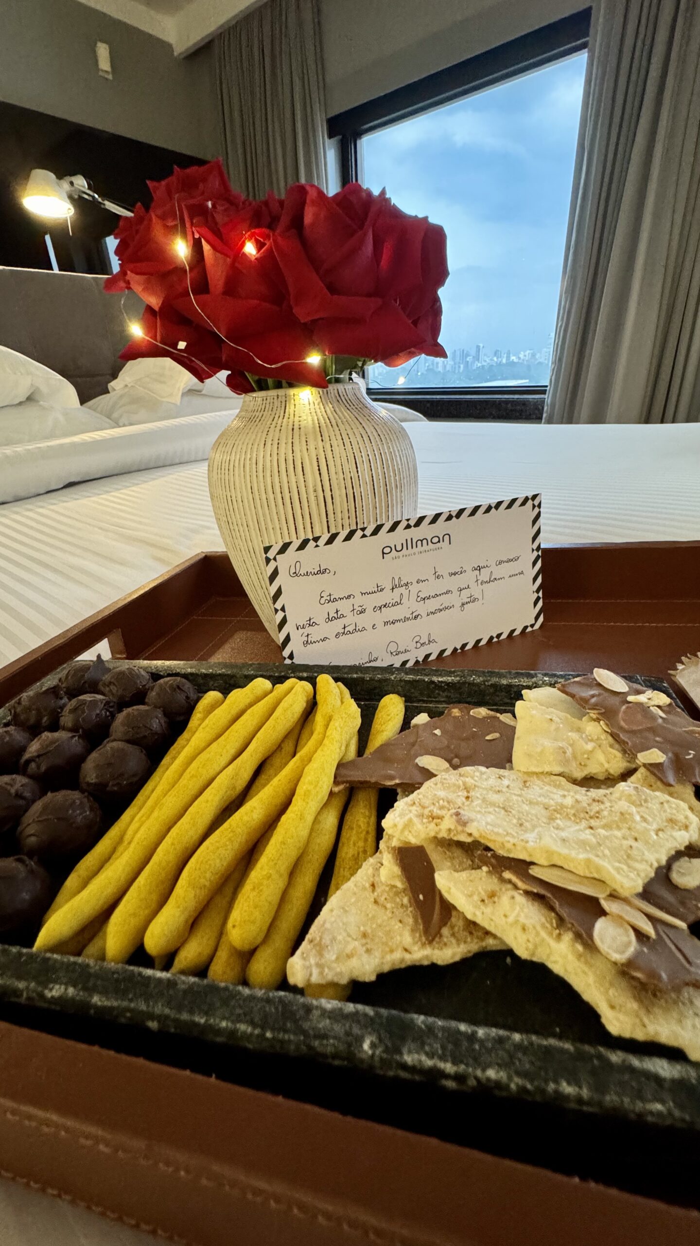 Bandeja com chocolates Dengo, biscoitos, buquê de rosas com LED e cartão personalizado do Pullman Ibirapuera na experiência ALL Accor