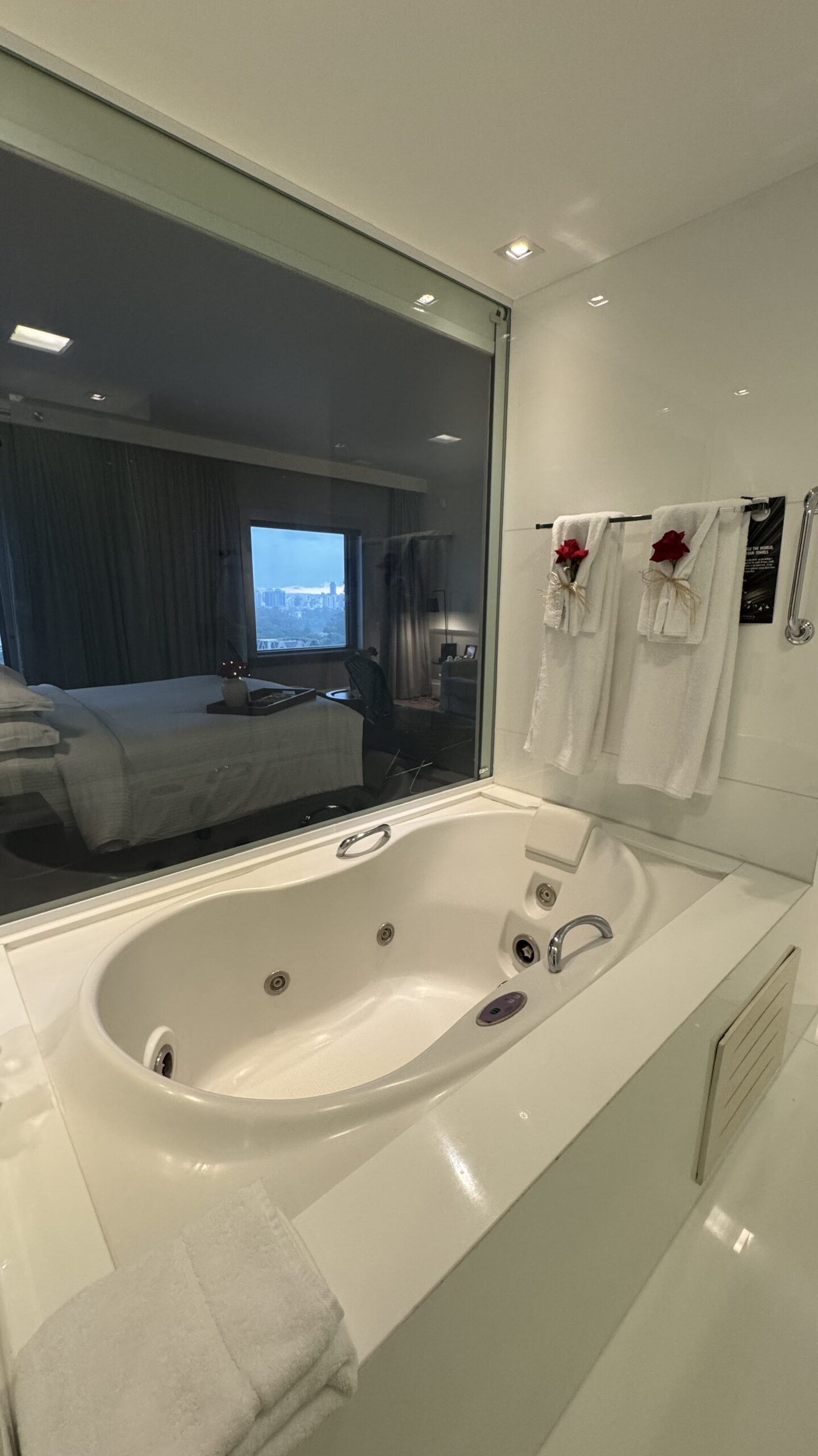 Jacuzzi da suíte executiva do Pullman Ibirapuera com vista para o quarto pelo vidro e toalhas decoradas com rosas