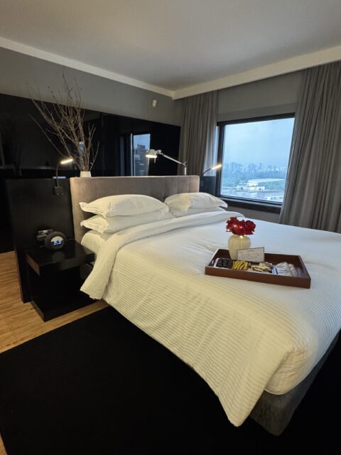 Cama king size da suíte executiva Trousseau no Pullman Ibirapuera com bandeja de chocolates Dengo e rosas da experiência romântica ALL Accor