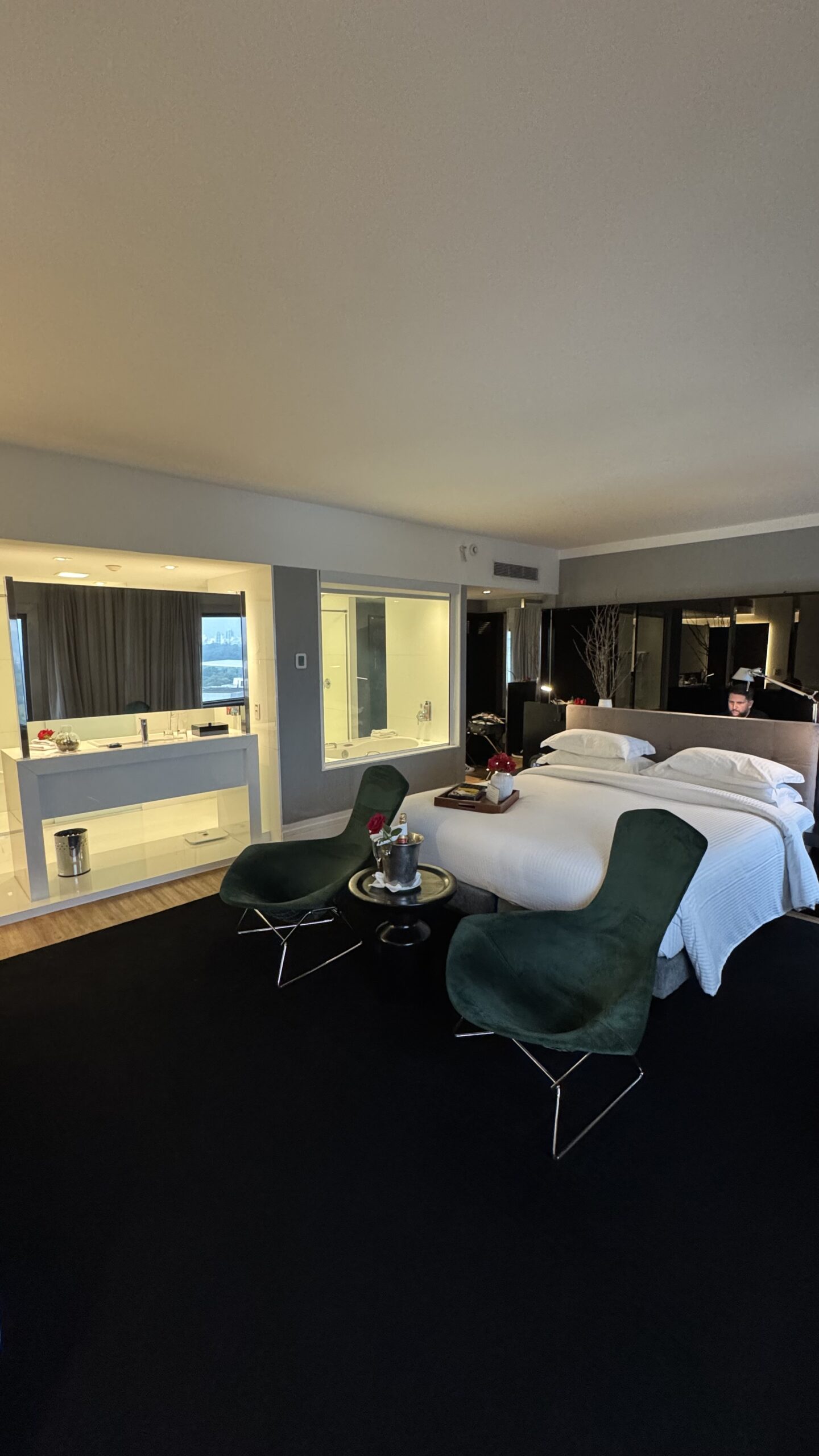Visão geral da suíte executiva do Pullman Ibirapuera com poltronas verdes, cama king size Trousseau e banheiro integrado ao fundo