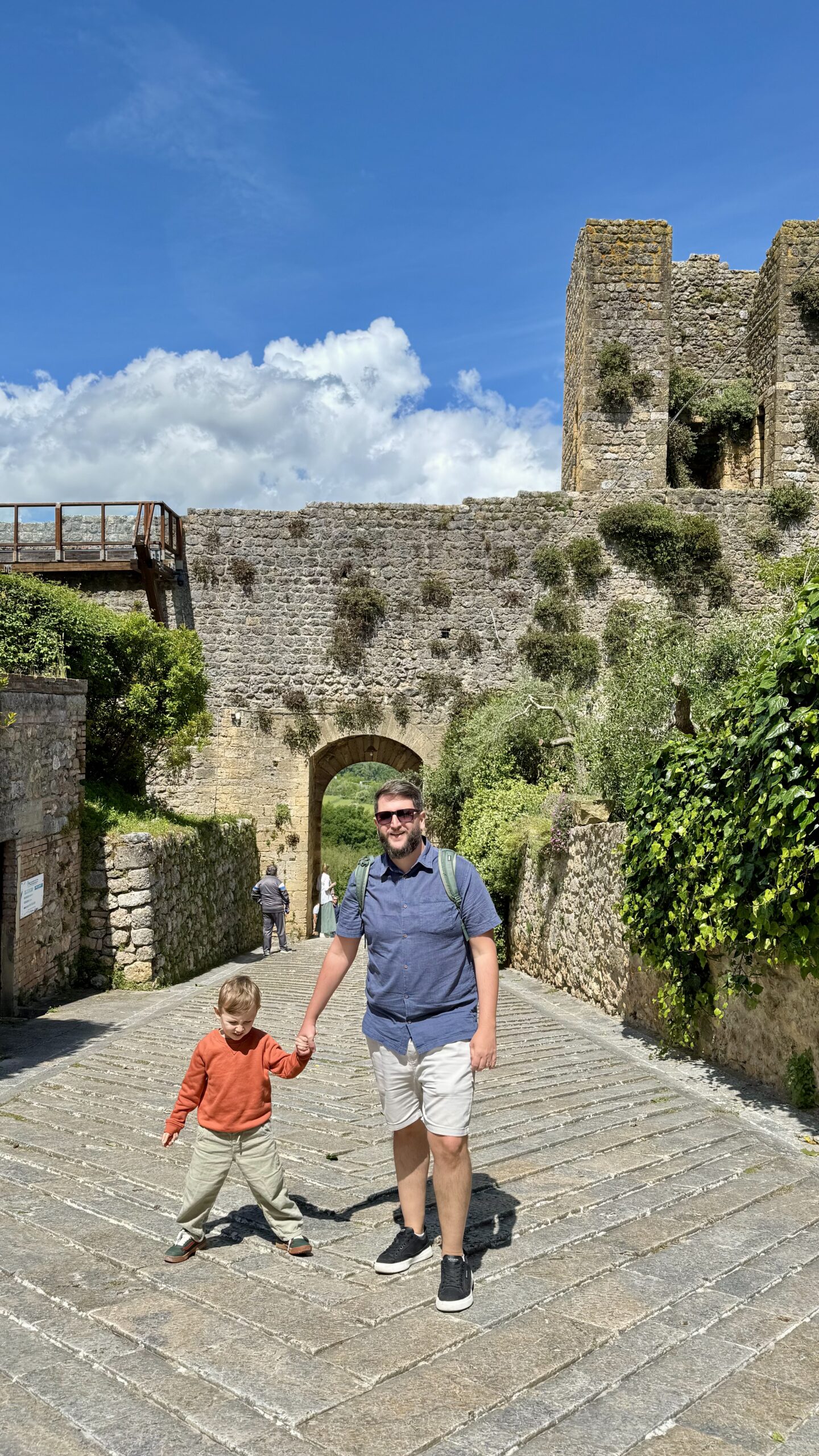 Rudi e Samuel de mãos dadas na entrada do arco medieval de Monteriggioni