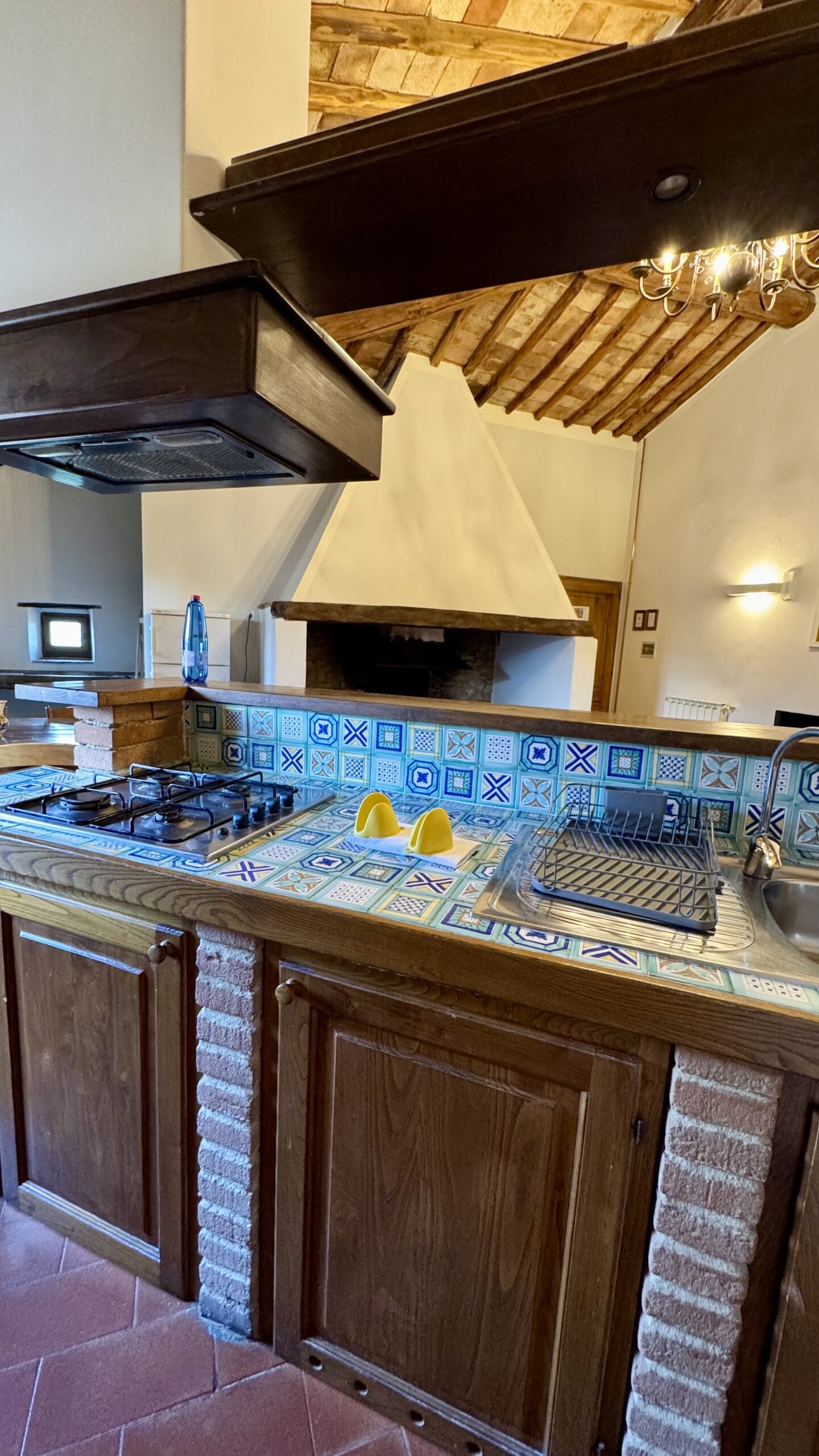 Cozinha do Riserva di Fizzano com azulejos coloridos e lareira de pedra