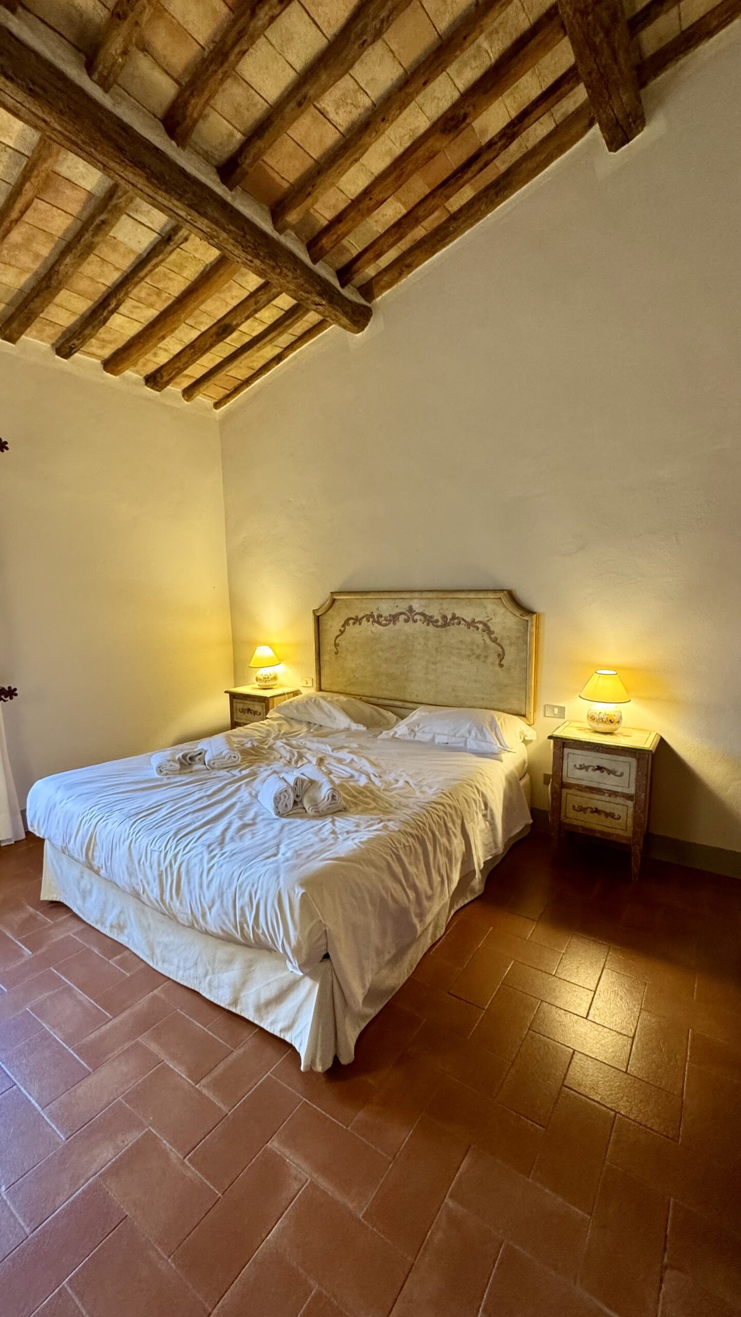 Quarto rústico do Riserva di Fizzano com vigas de madeira e piso de terraço