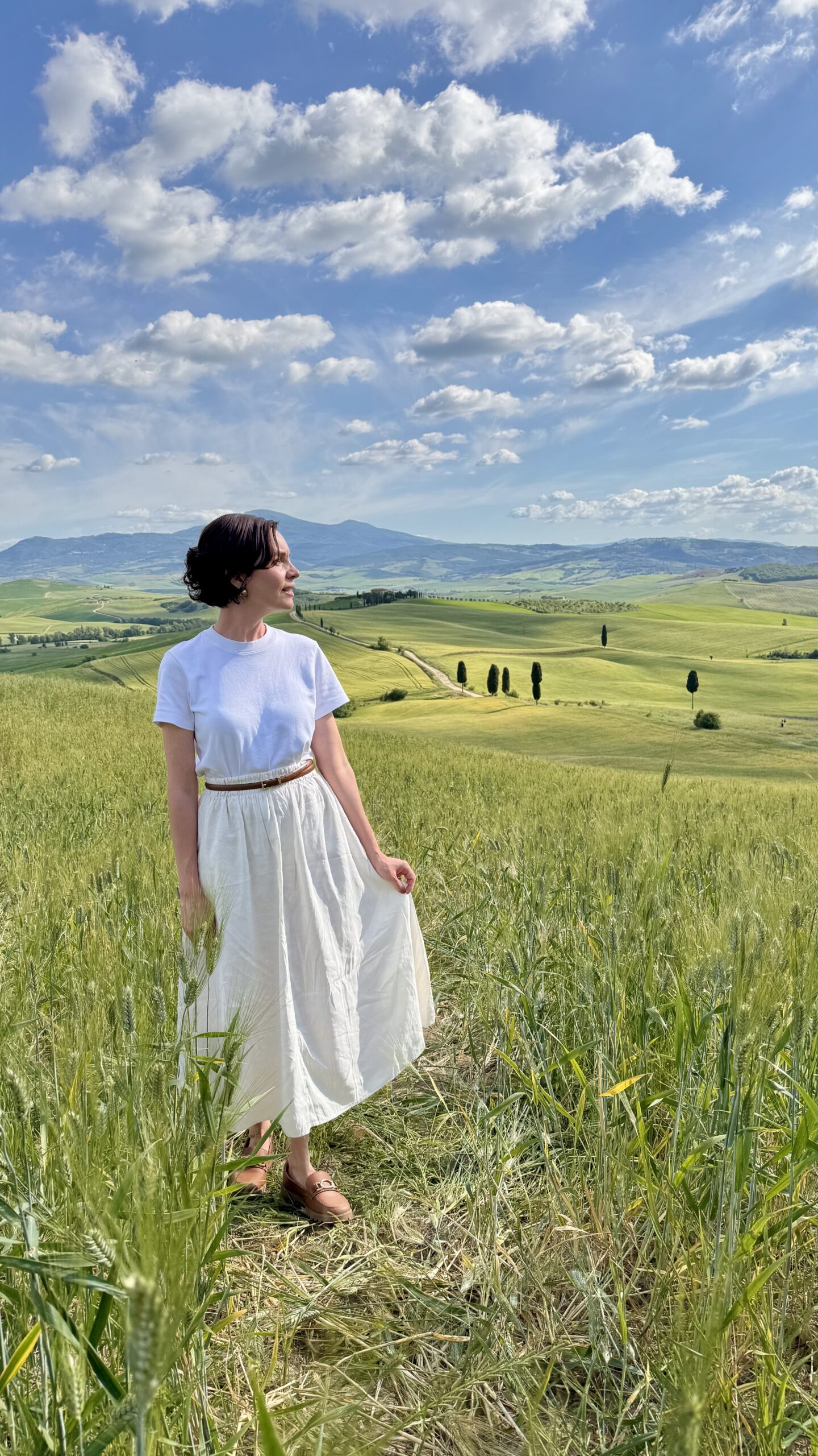 Carol no campo de trigo do Val d'Orcia com ciprestes e colinas ao fundo