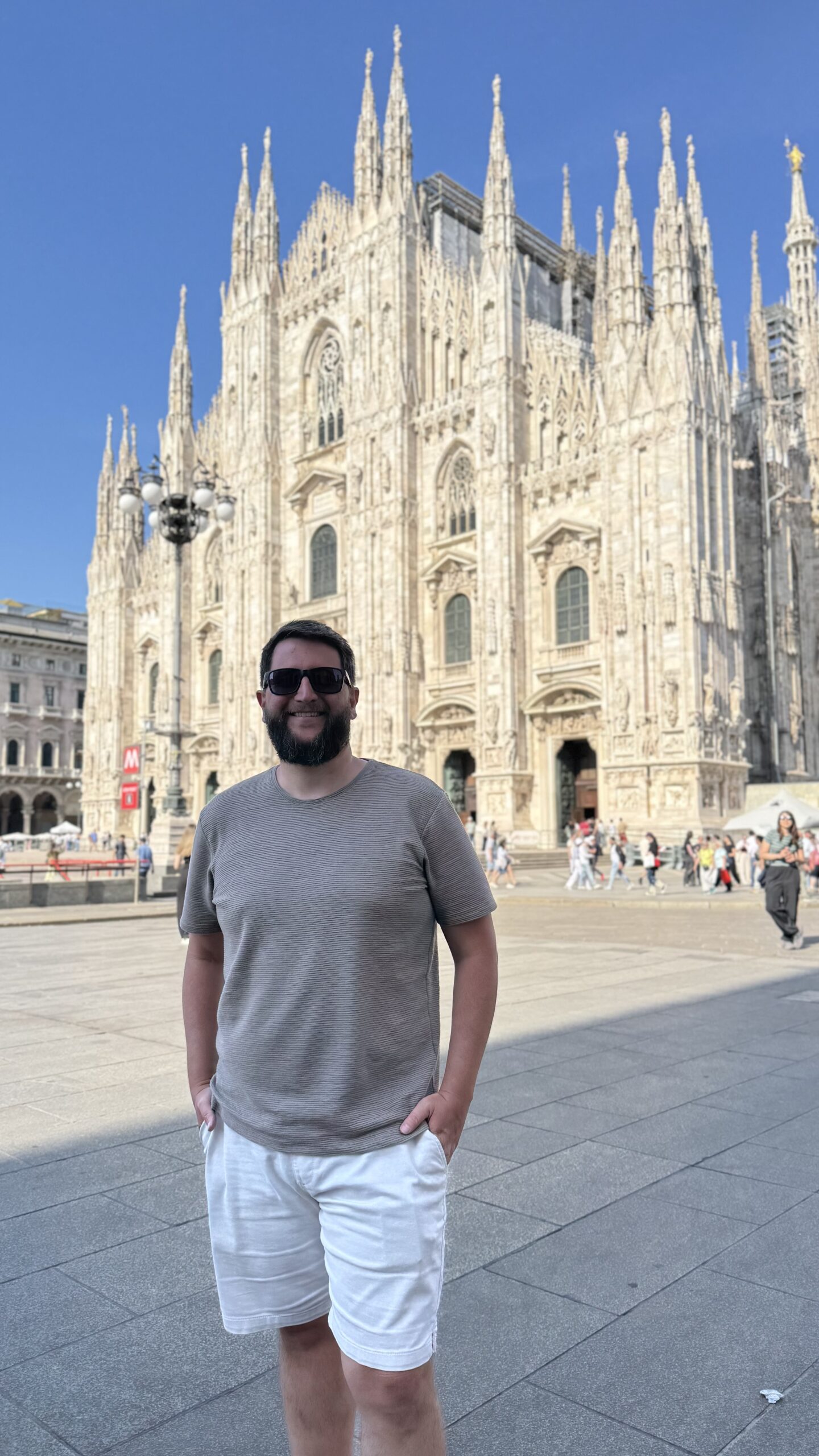Homem em pe na Piazza del Duomo, com a fachada gotica da catedral ao fundo