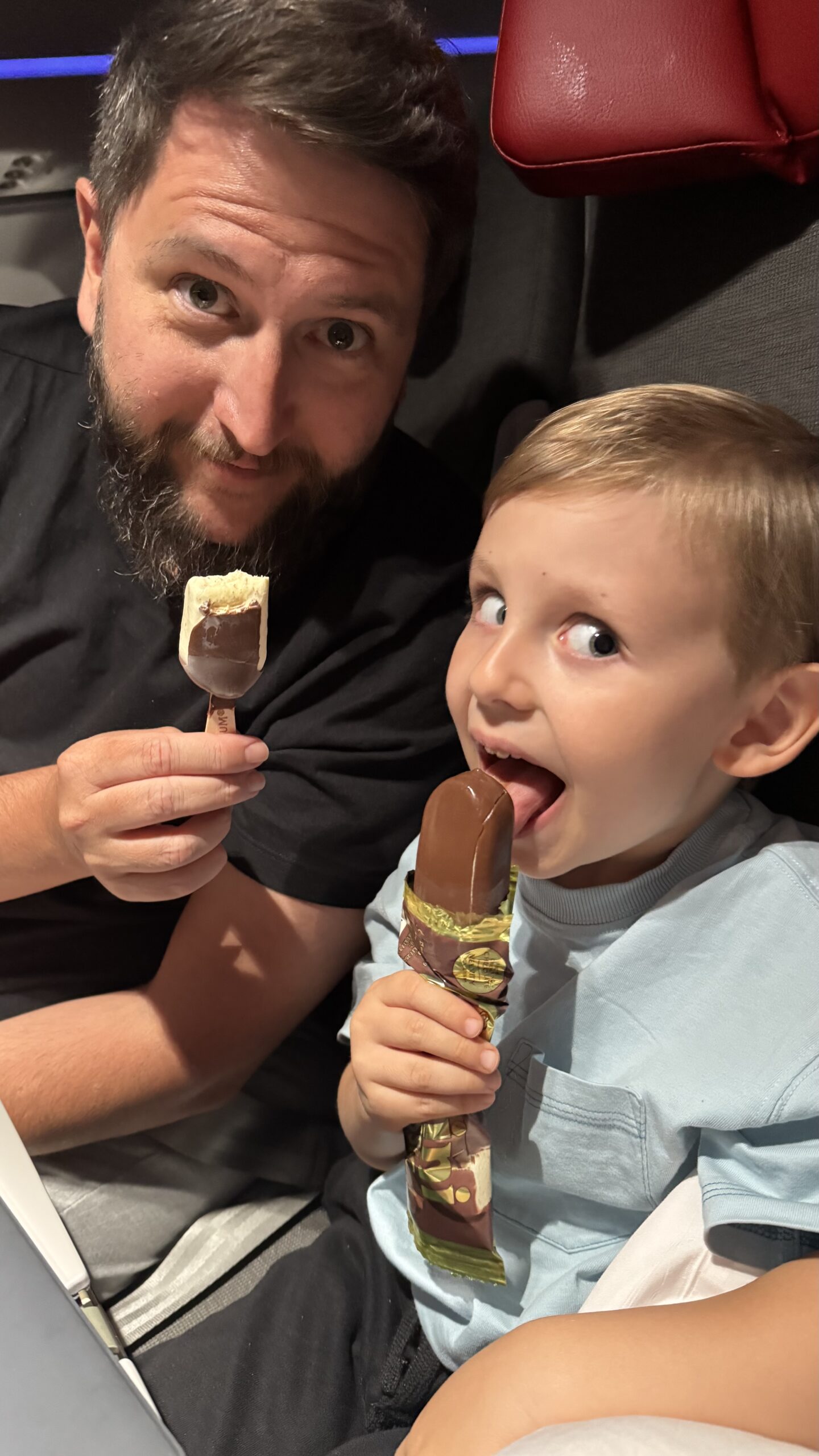 Rudi e Samuel comendo sorvete Magnum mini durante o voo