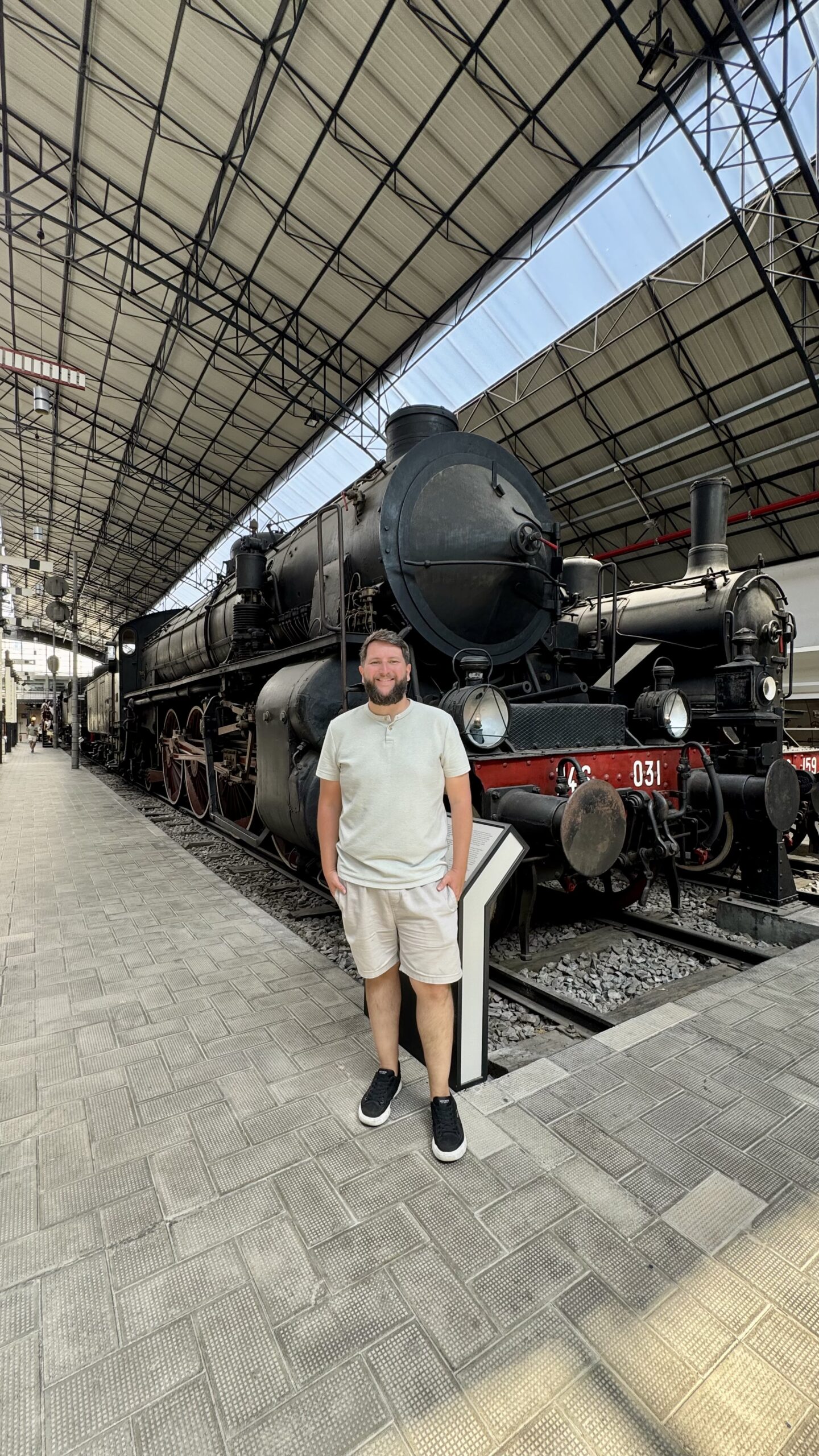 Rudi em frente a uma locomotiva a vapor preta exposta no museu ferroviario de Milao