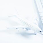 Miniatura de avião ao lado de um teclado de computador, representando pesquisa de passagem aérea online