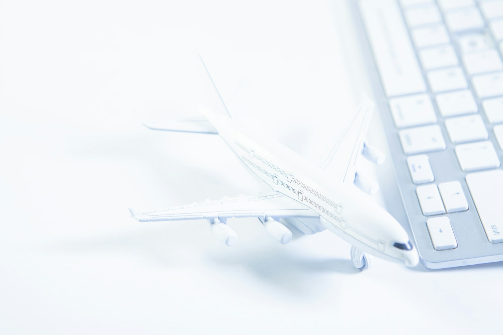 Miniatura de avião ao lado de um teclado de computador, representando pesquisa de passagem aérea online