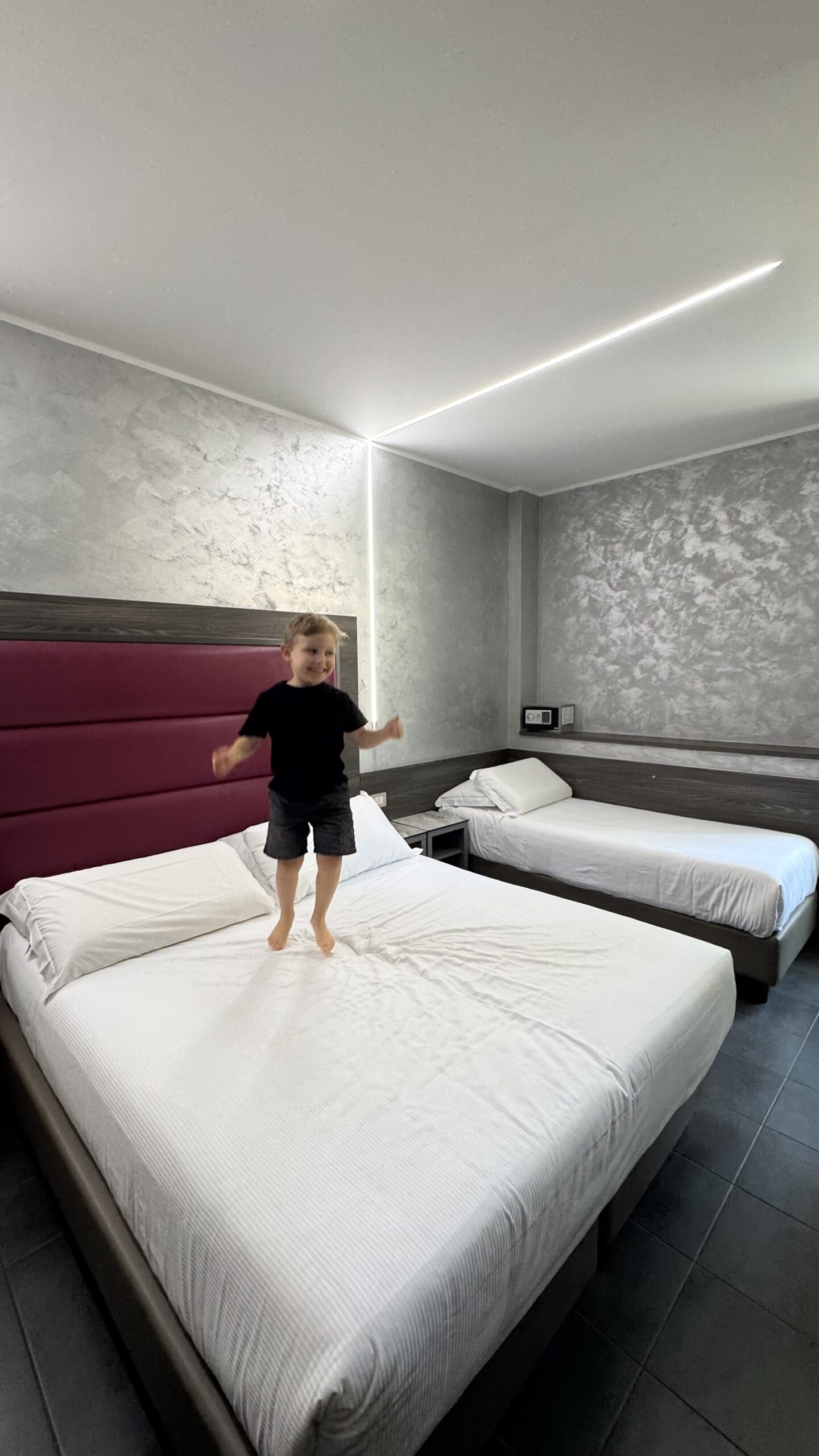Samuel pulando na cama do quarto do Ibis Styles Milão