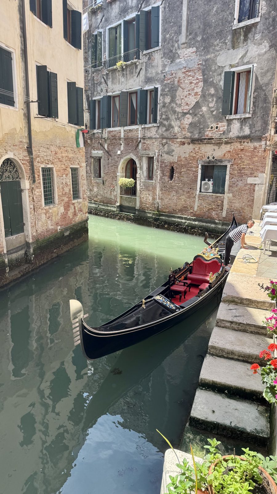 Gôndola preta atracada em canal estreito entre prédios históricos de Veneza
