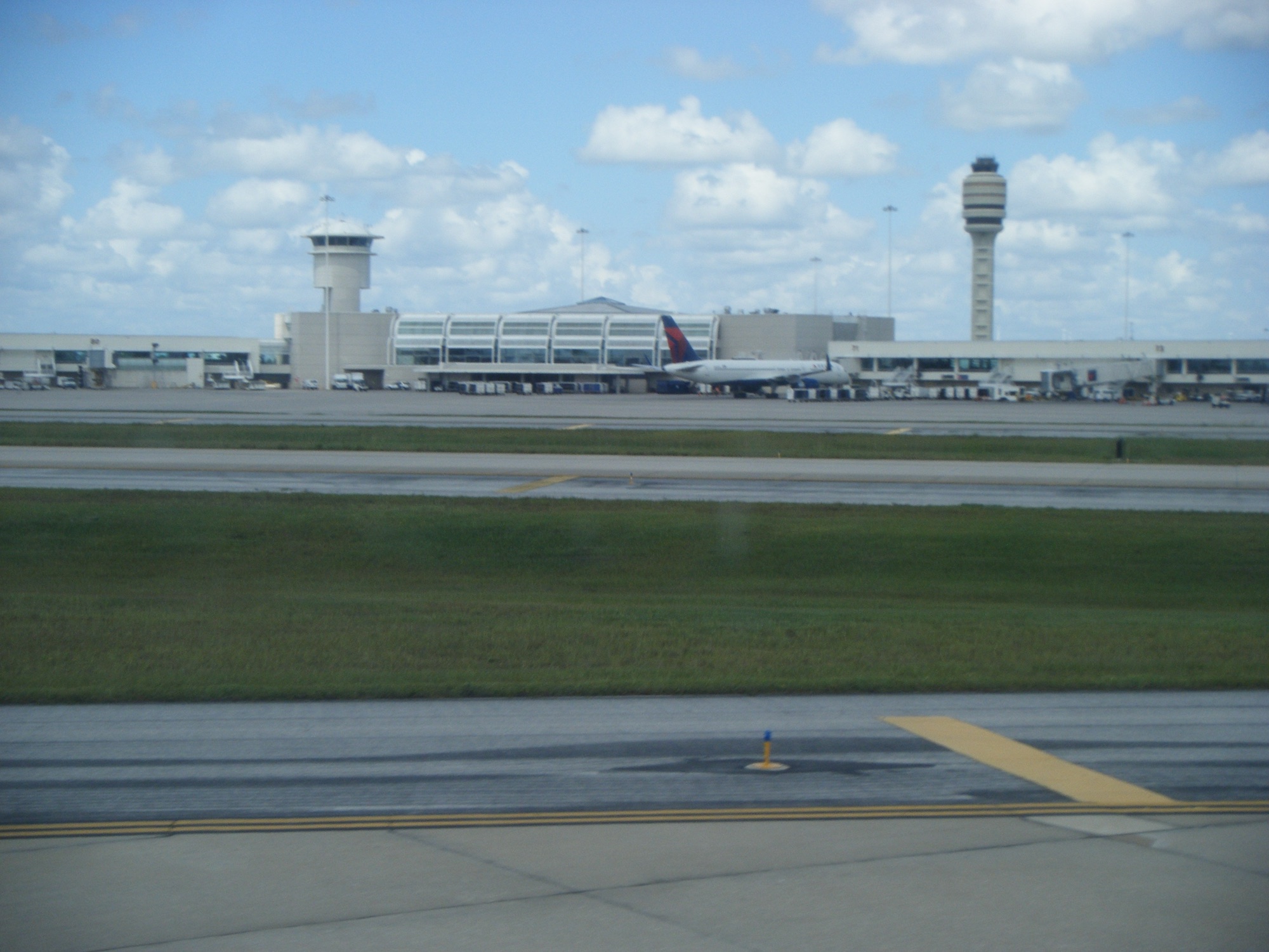 Terminal do Aeroporto de Orlando MCO visto do patio com torre de controle ao fundo