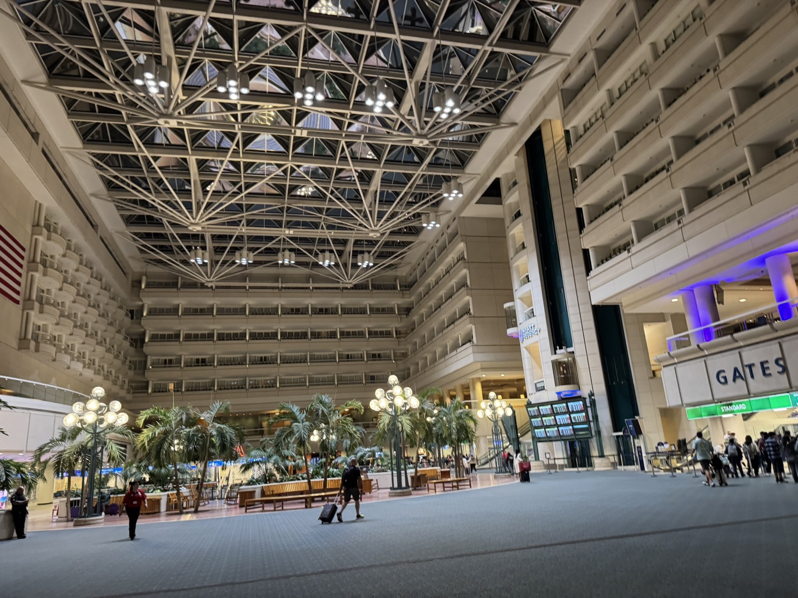 Saguao principal do Aeroporto Internacional de Orlando com teto de vidro e palmeiras internas
