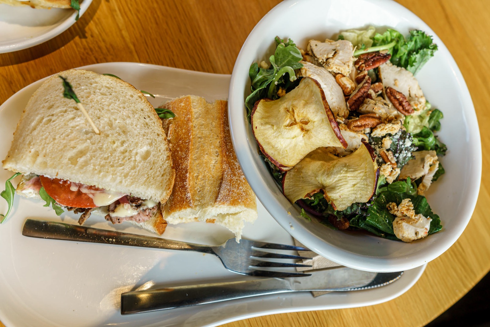 Prato com sanduiche e tigela de salada com frango e nozes em restaurante de Disney Springs