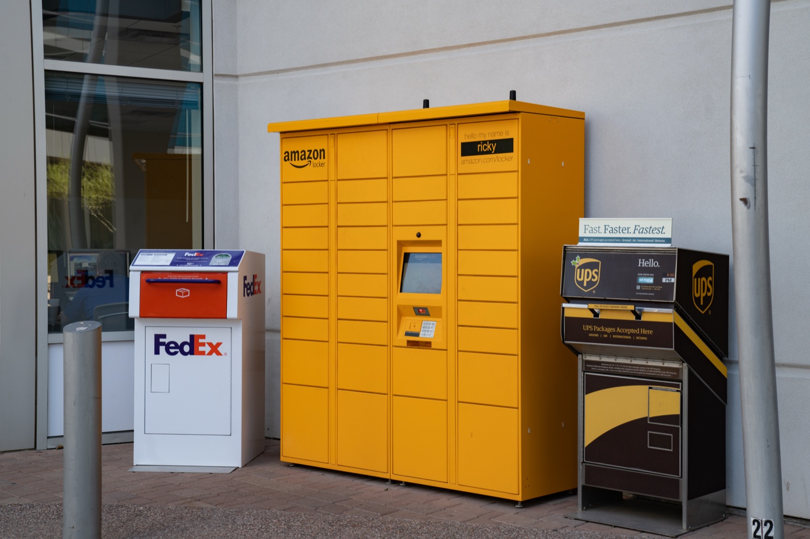 Amazon Locker amarelo instalado ao lado de caixas de coleta FedEx e UPS em calcada