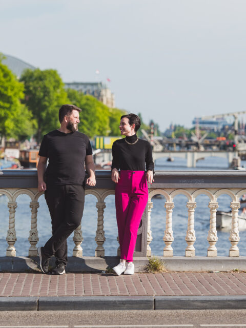 Casal com o bebe no colo em uma ponte cercada de bicicletas com um canal de Amsterda ao fundo, em ensaio fotografico profissional