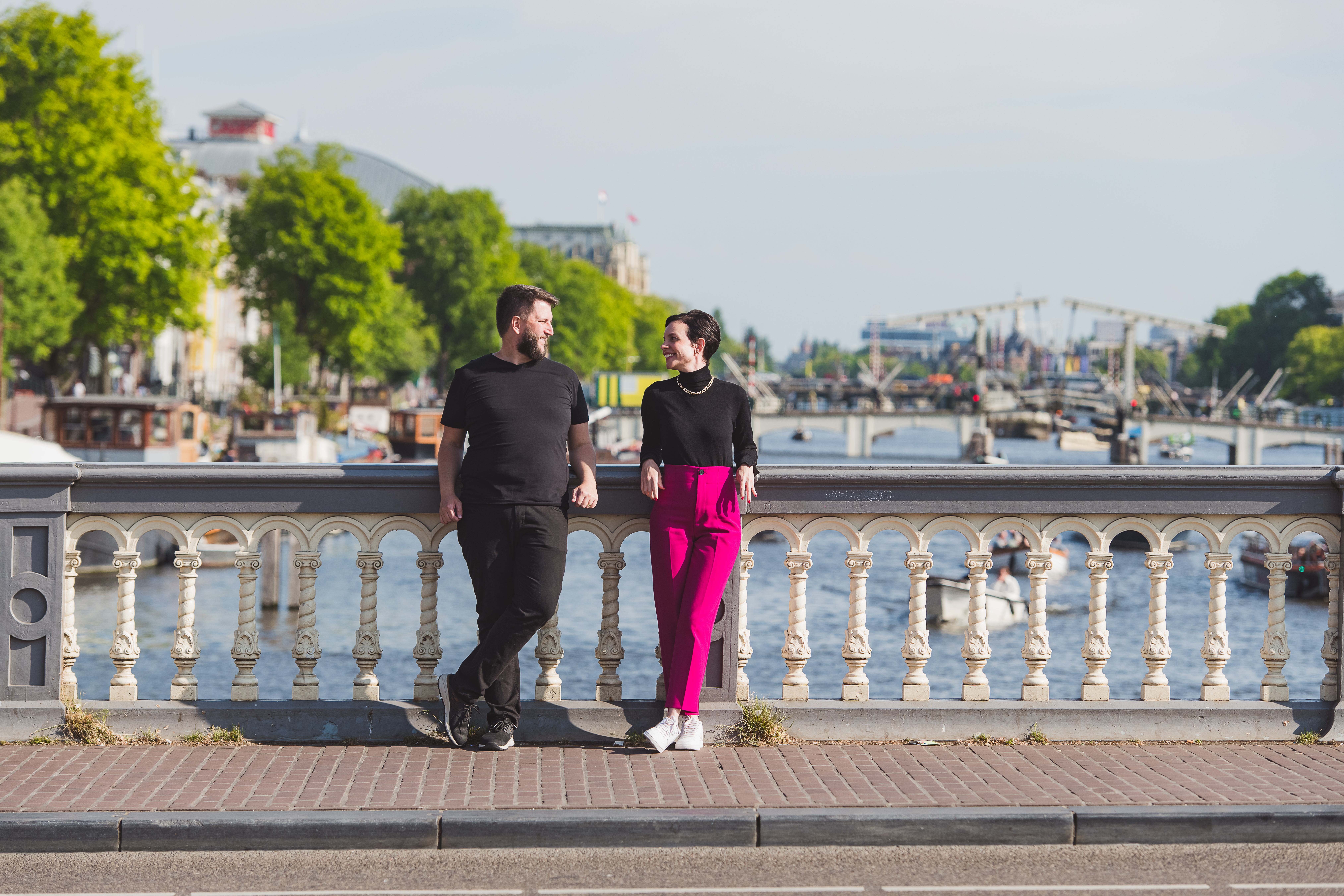 Casal com o bebe no colo em uma ponte cercada de bicicletas com um canal de Amsterda ao fundo, em ensaio fotografico profissional
