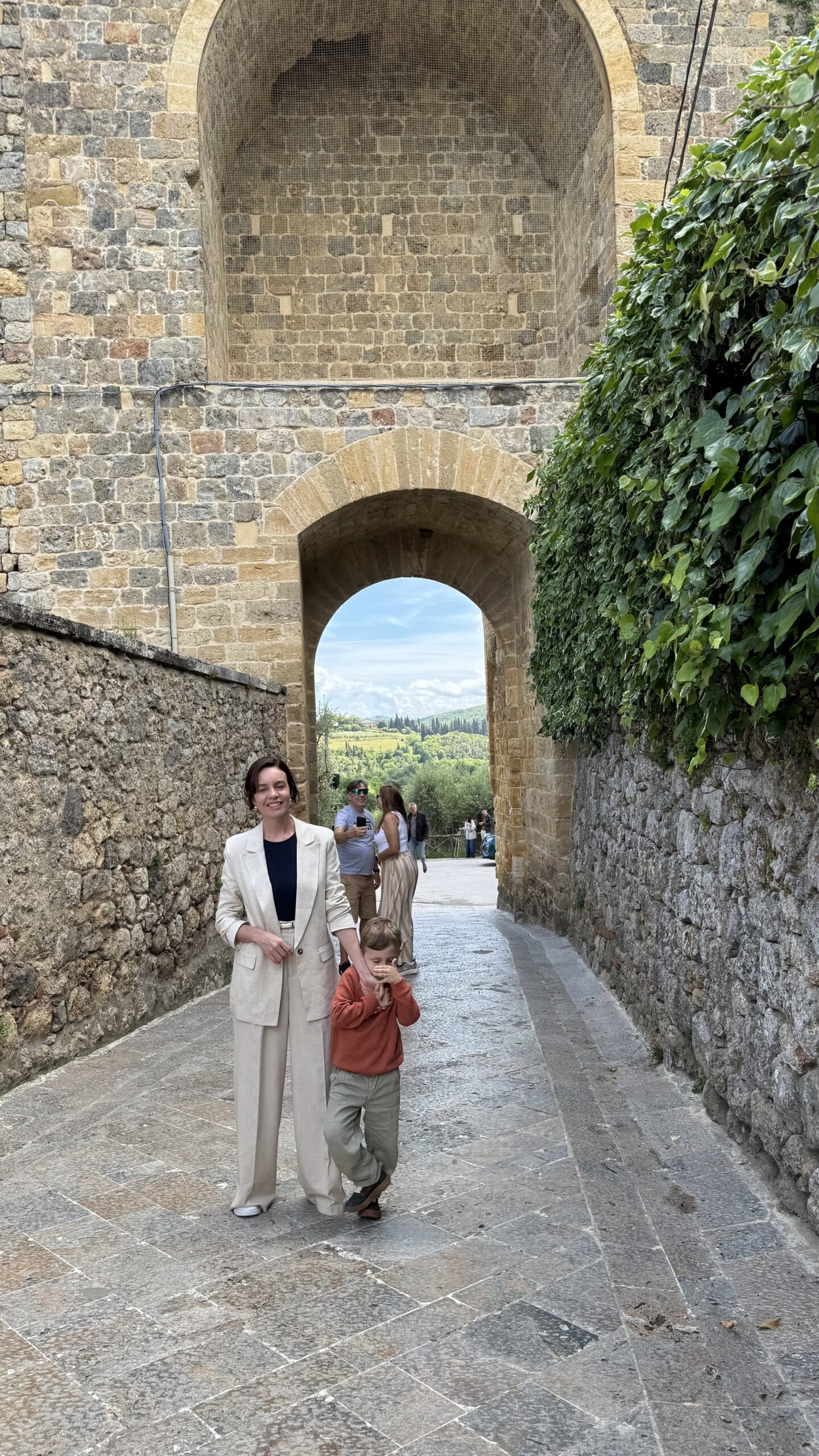 Arco de pedra na saída das muralhas de Monteriggioni, com a paisagem verde do campo toscano visível através da abertura