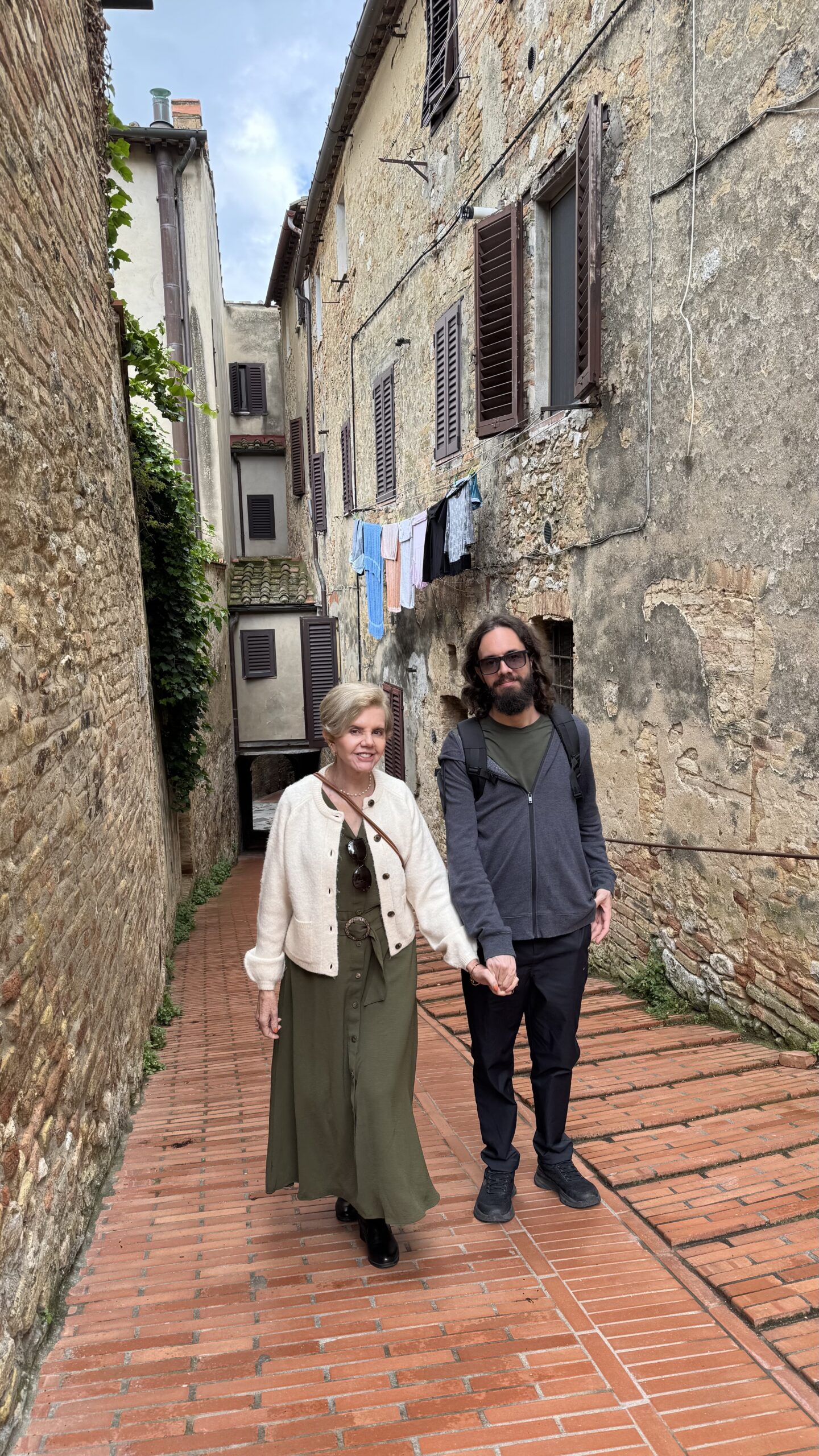 Beco estreito de pedra em San Gimignano com roupas estendidas num varal entre os prédios