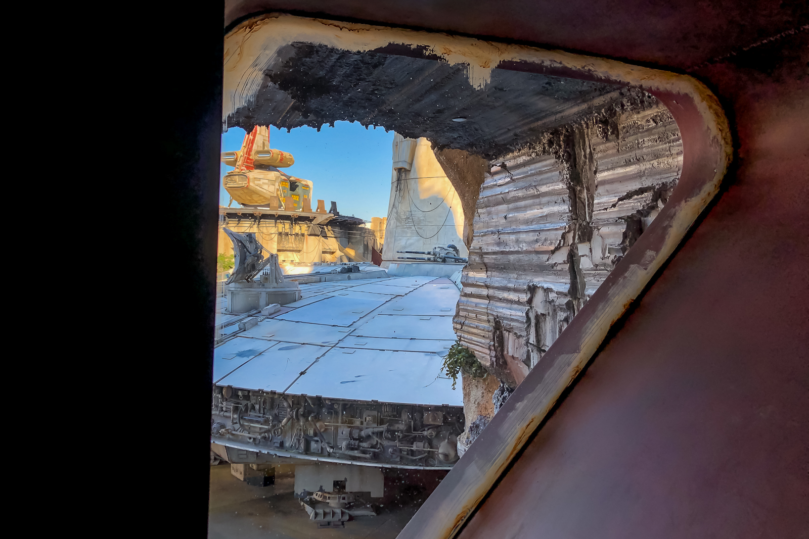 Pátio de Black Spire Outpost visto através de abertura de nave, com veículo alaranjado e formações rochosas