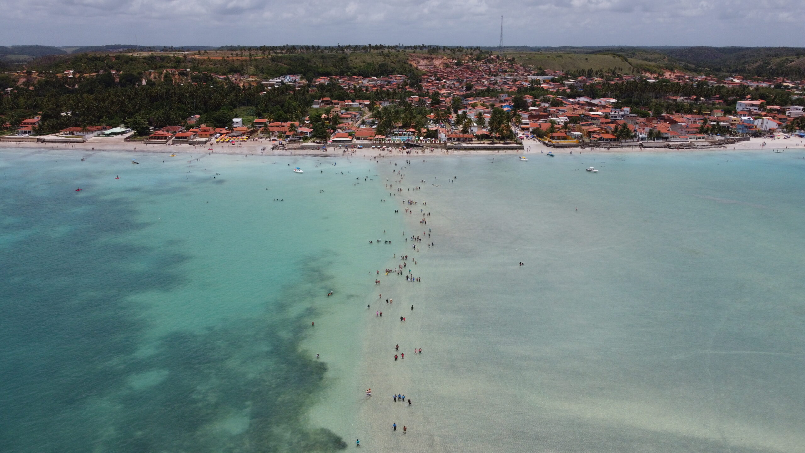 Vista aérea de drone da faixa de areia do Caminho de Moisés com o vilarejo de Barra Grande e coqueiros ao fundo.