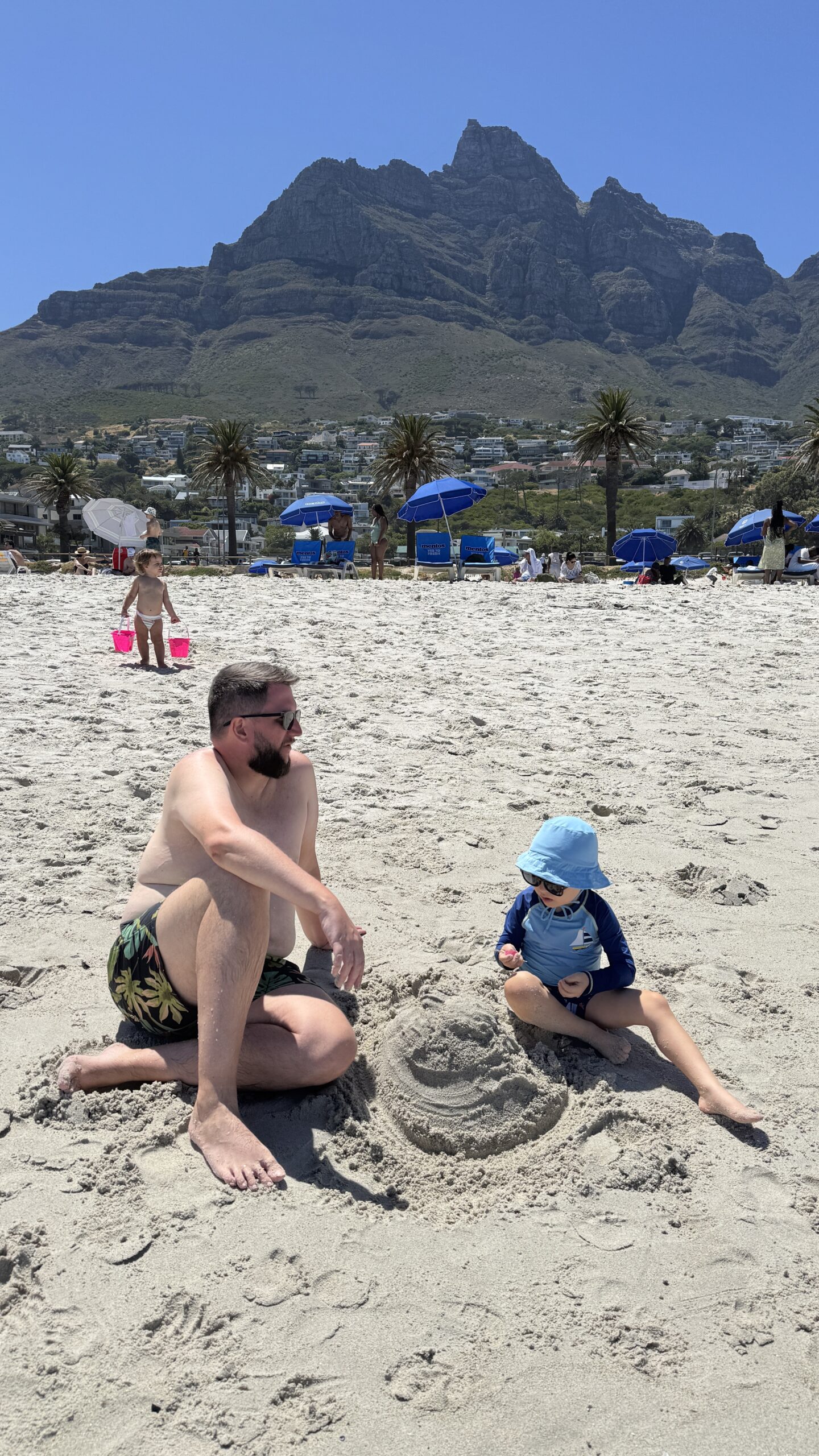 Rudi e Samuel fazendo castelo de areia em Camps Bay com a Table Mountain ao fundo