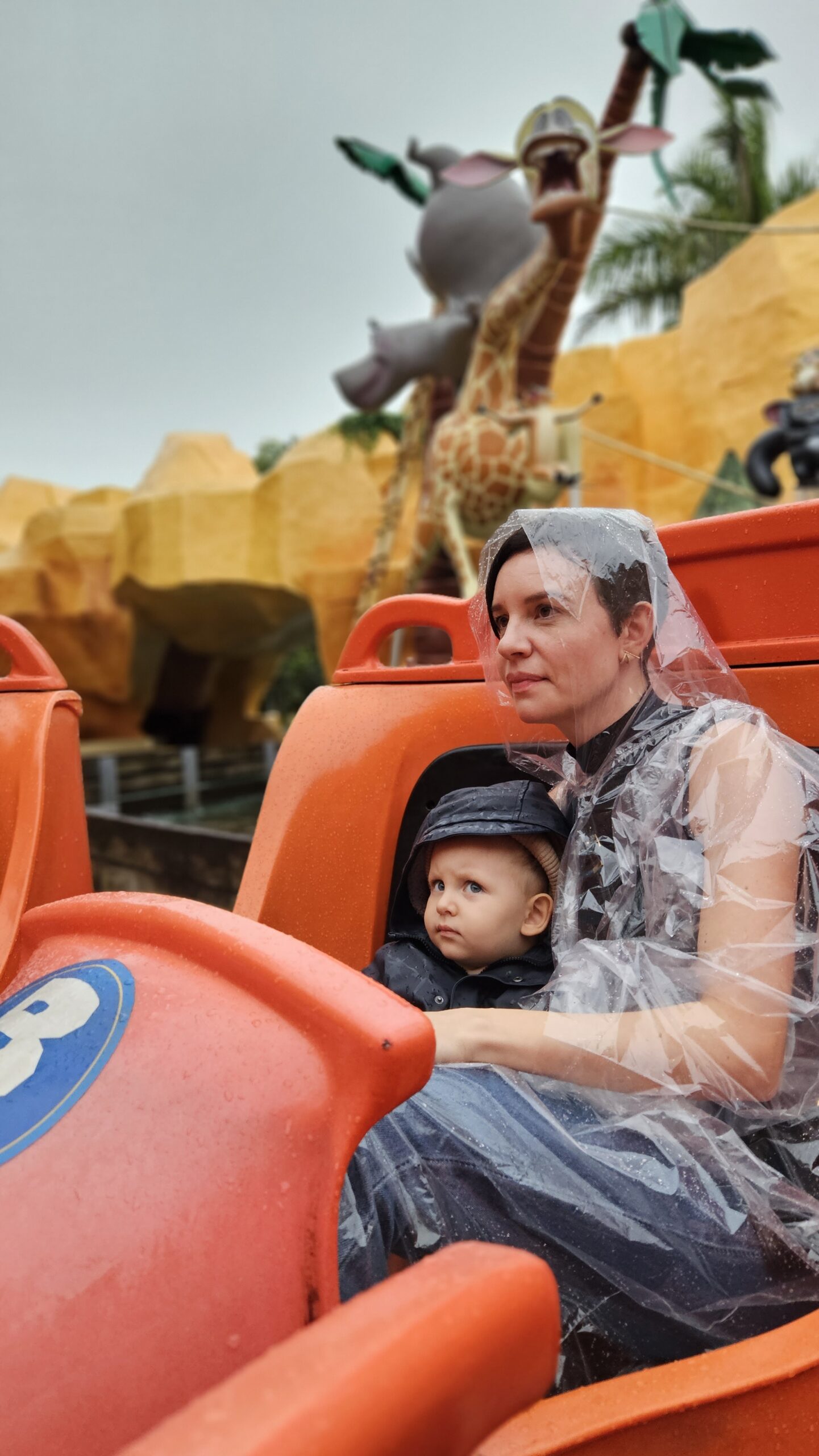 Mãe de capa de chuva plástica com Sam no colo numa atração do Beto Carrero World