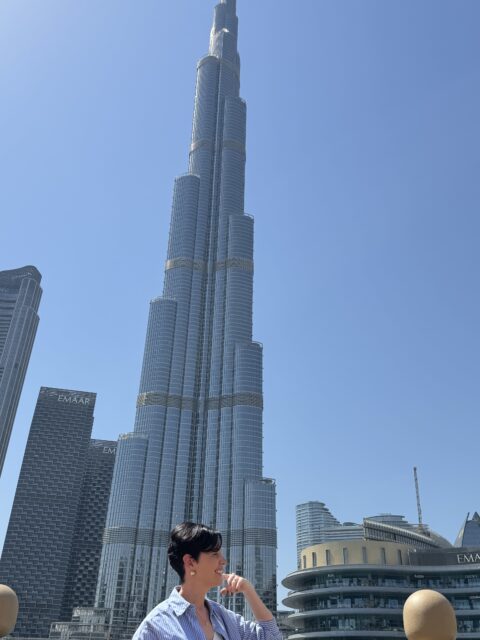 Rudi e a esposa em frente à fonte de Dubai, com o Burj Khalifa refletido atrás