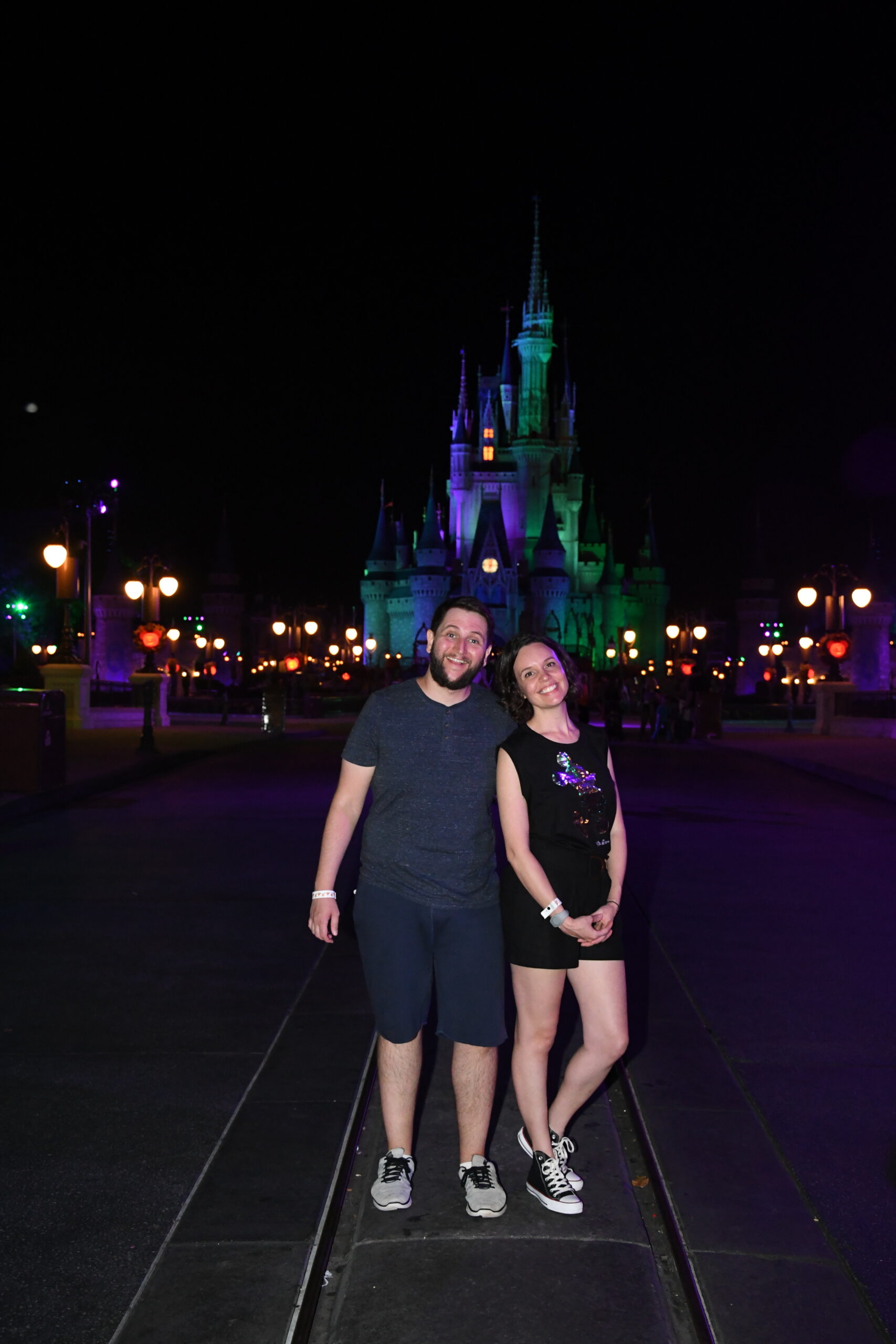 Casal em frente ao Castelo da Cinderela iluminado à noite no Magic Kingdom