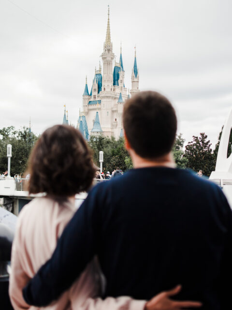 Casal abraçado de costas observando o Castelo da Cinderela durante ensaio fotográfico no Magic Kingdom