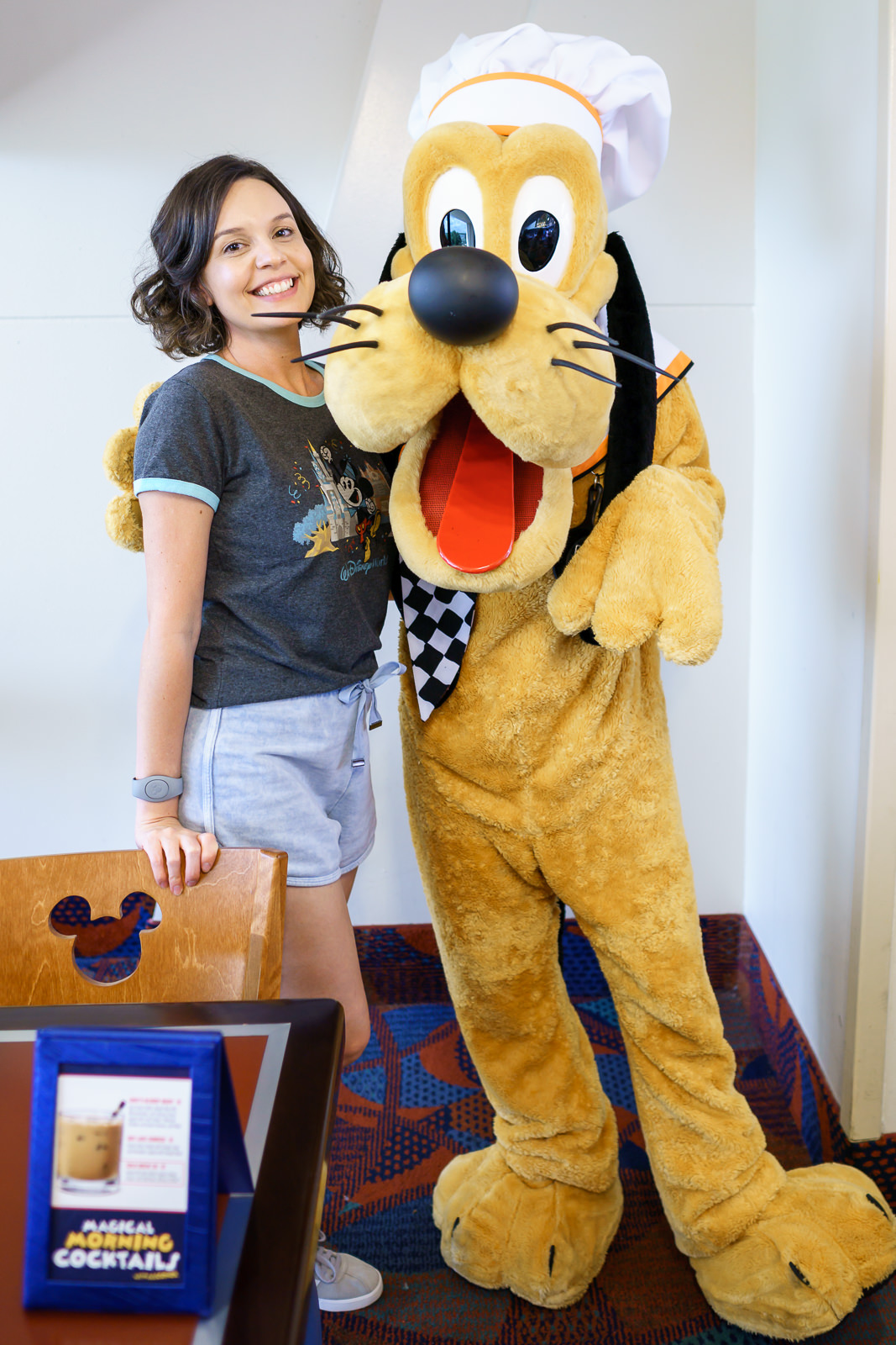 Pluto interagindo com hóspedes à mesa durante refeição com personagens no Chef Mickey's
