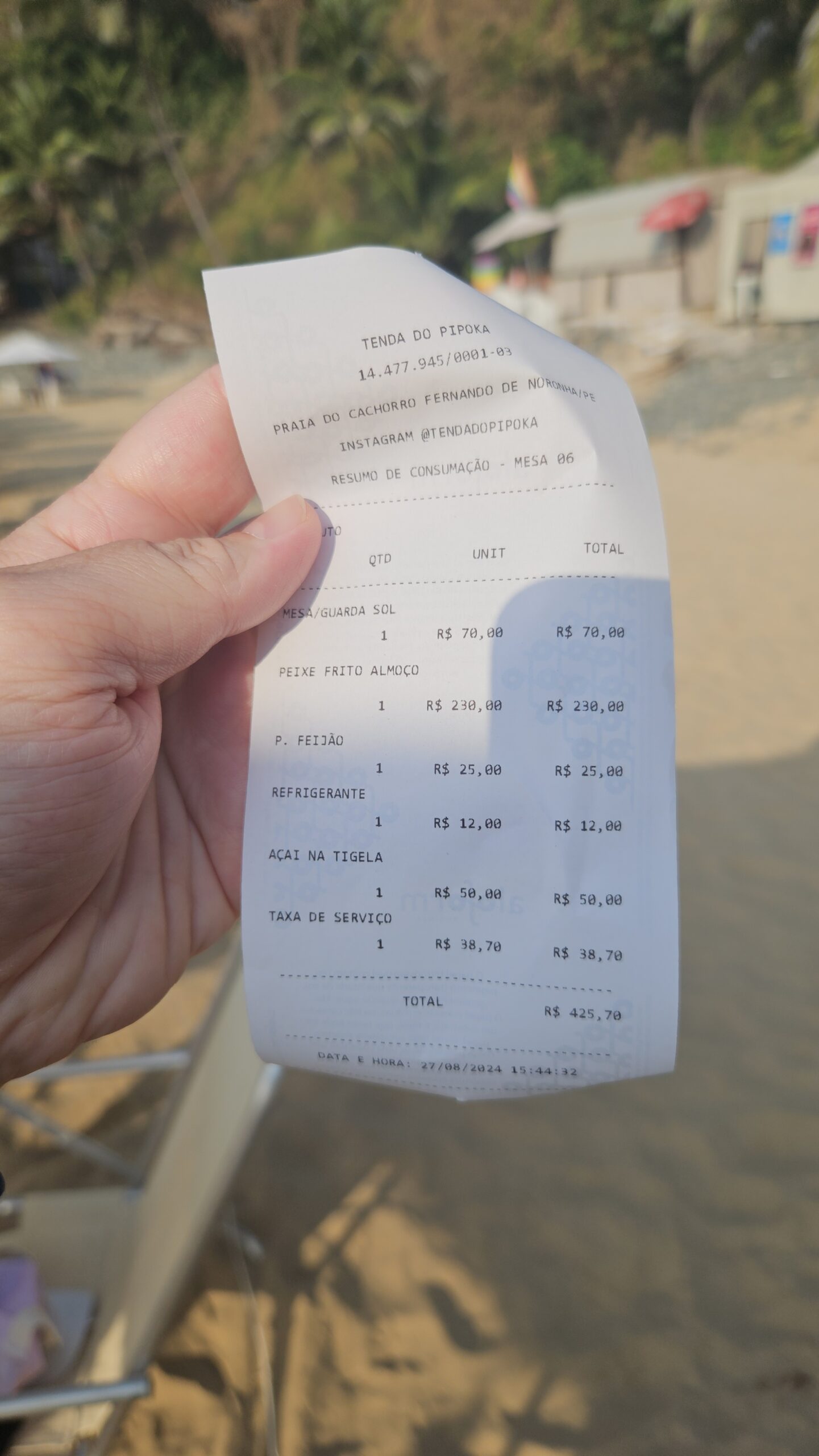 Comprovante da Tenda do Pipoka segurado na areia da Praia do Cachorro
