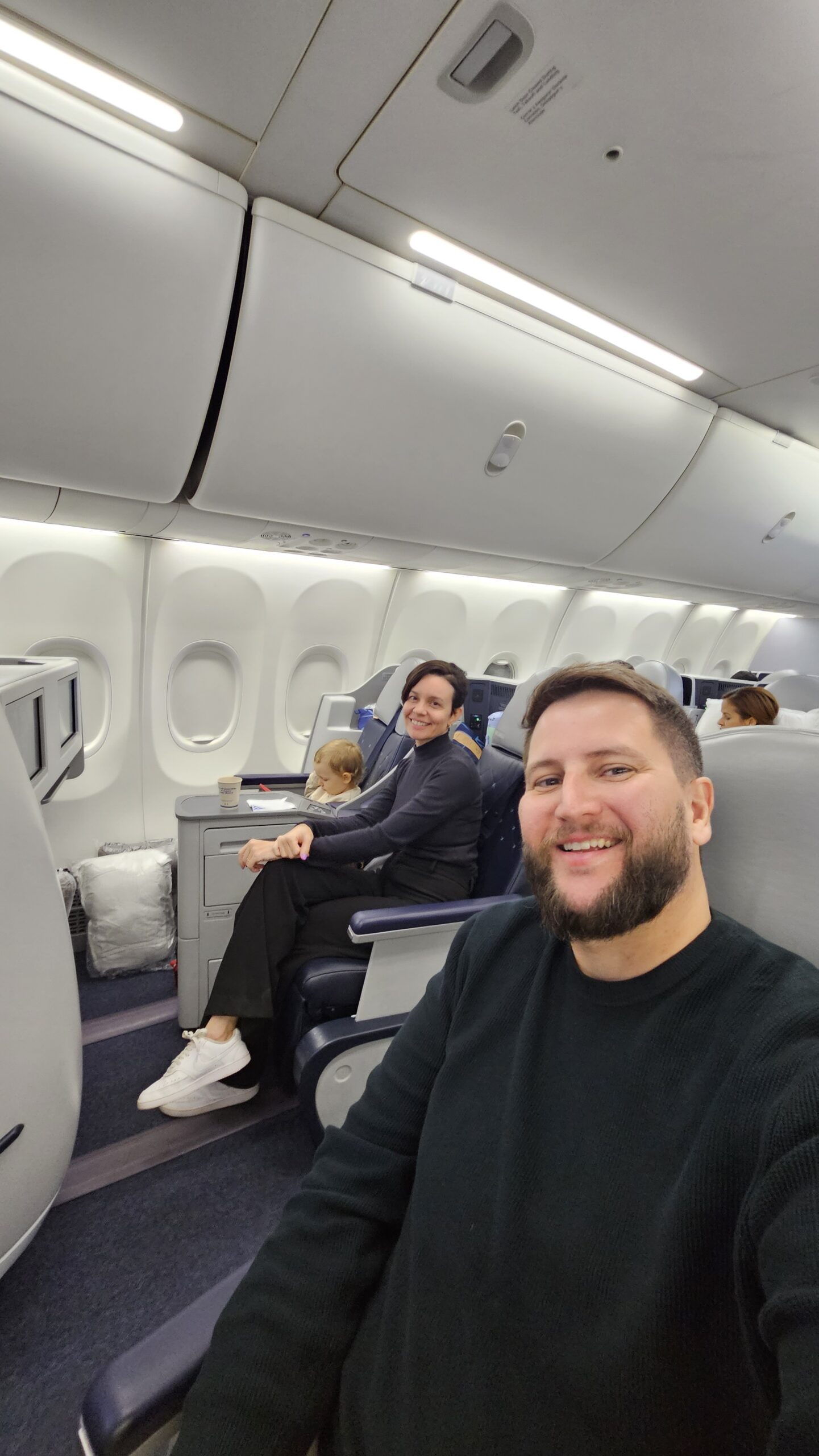 Rudi com Samuel no colo recebido pela comissária na cabine Dreams da Copa Airlines