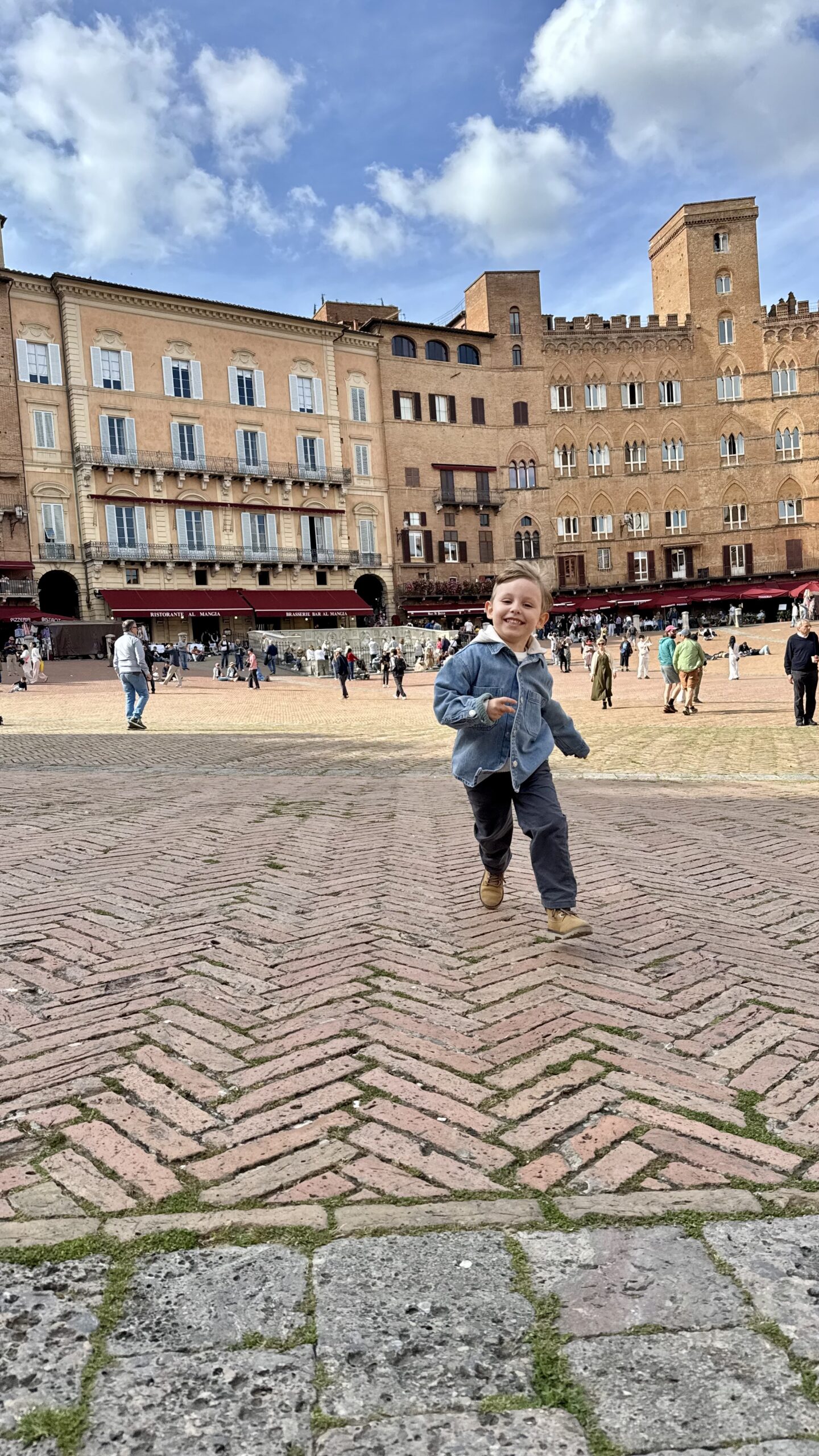 Criança correndo na Piazza del Campo em Siena, com o Palazzo Pubblico ao fundo
