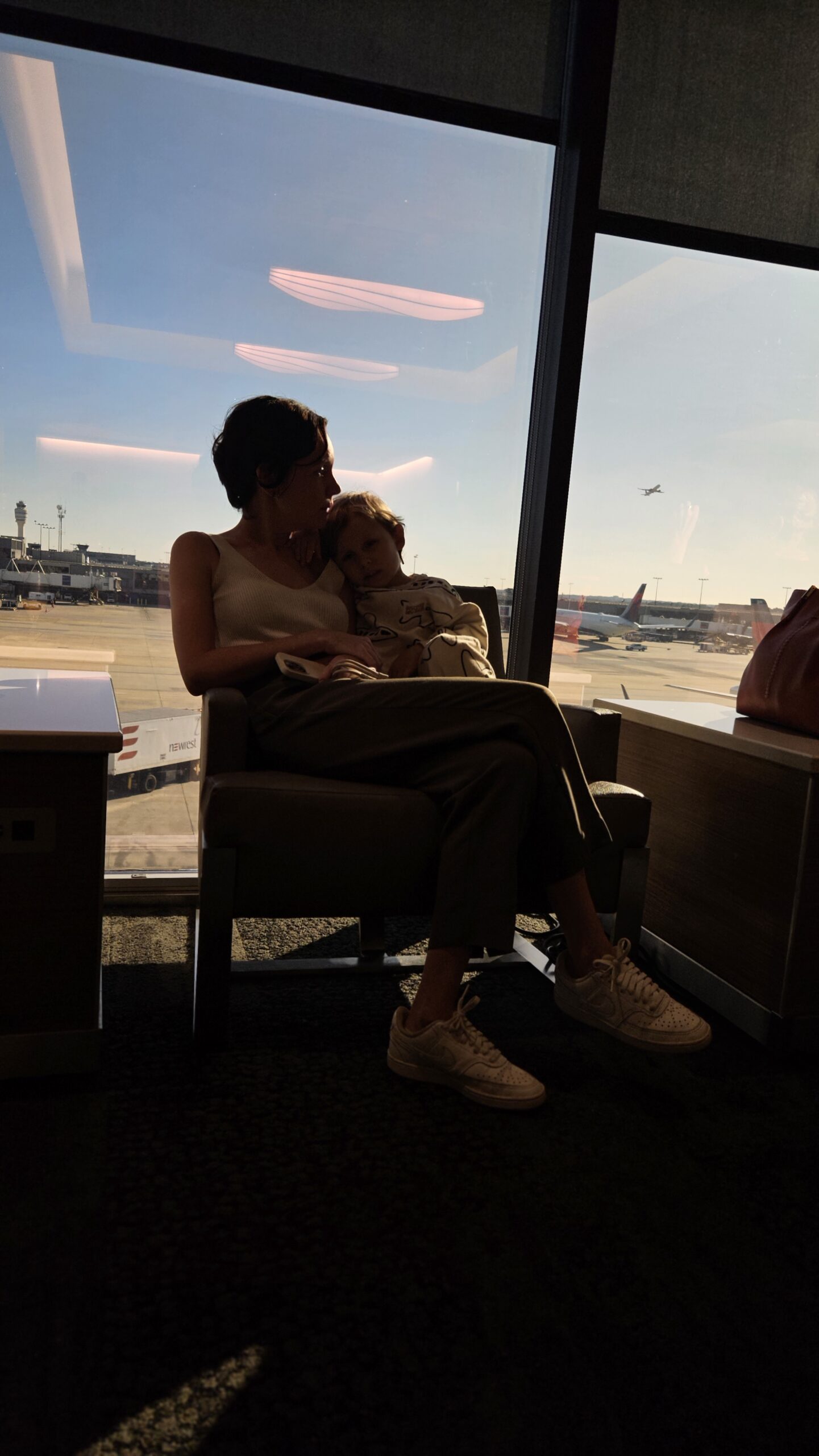 Samuel no colo observando os aviões pela janela do Delta Sky Club em Atlanta