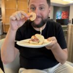 Rudi comendo camarão e sanduíche no Delta Sky Club de Atlanta
