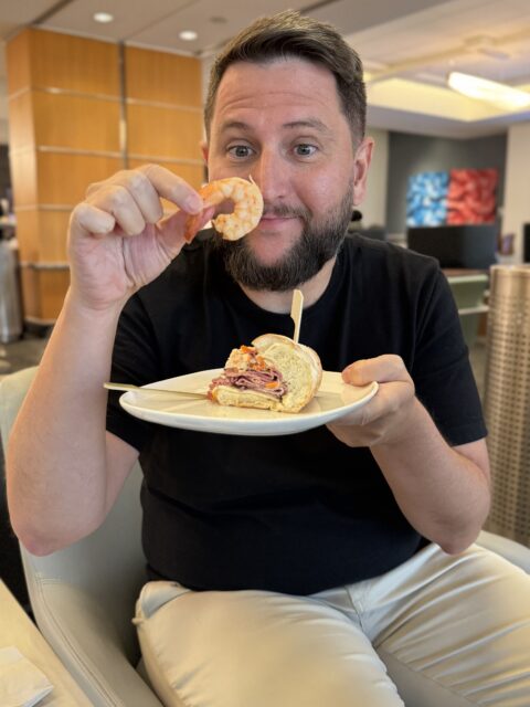 Rudi comendo camarão e sanduíche no Delta Sky Club de Atlanta