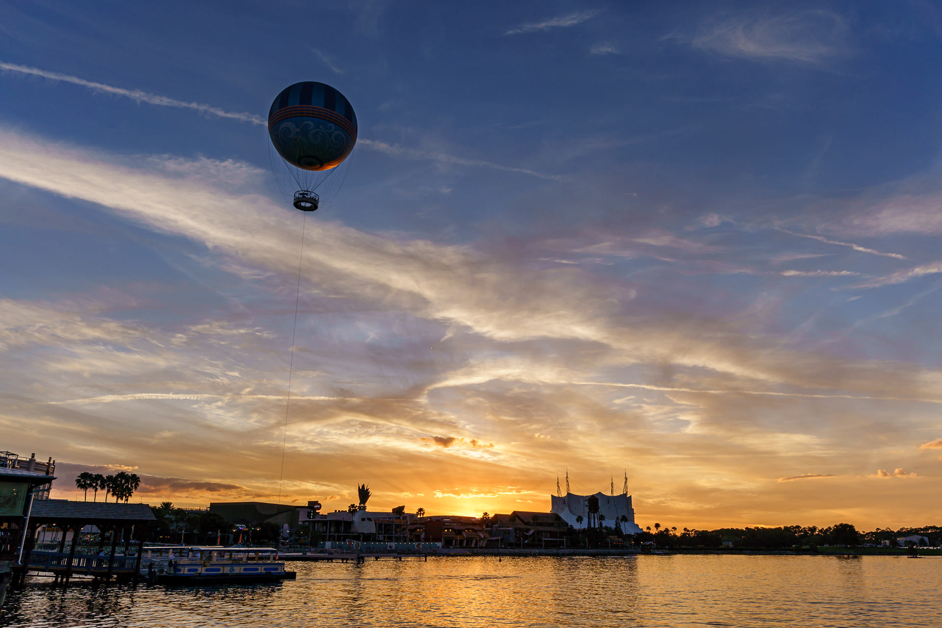 Balao do Aerophile subindo ao entardecer sobre a lagoa de Disney Springs com ceu em tons de laranja e roxo