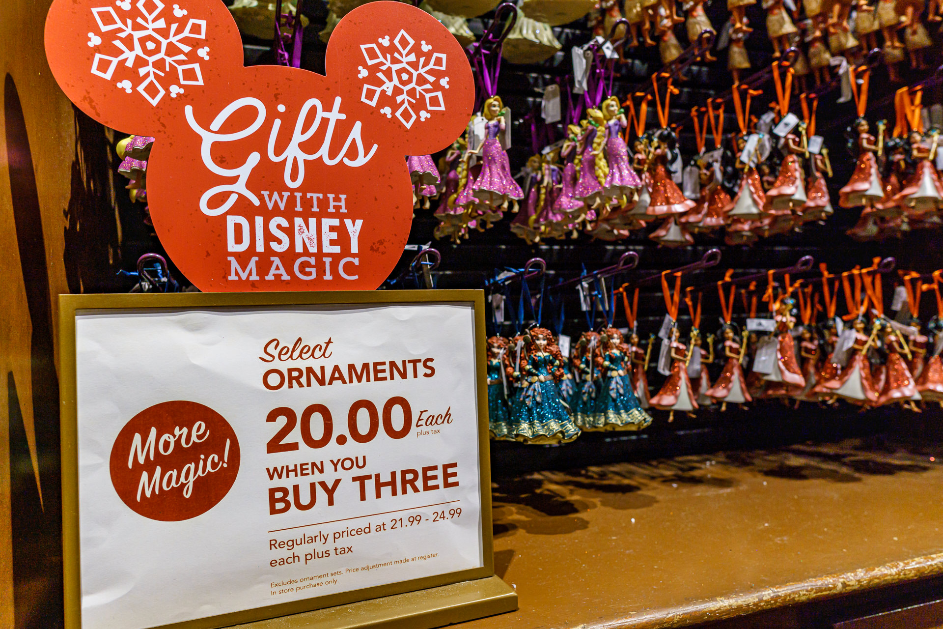 Loja de enfeites e ornamentos natalinos da Disney em Disney Springs, com placa de promoção e bonecas penduradas