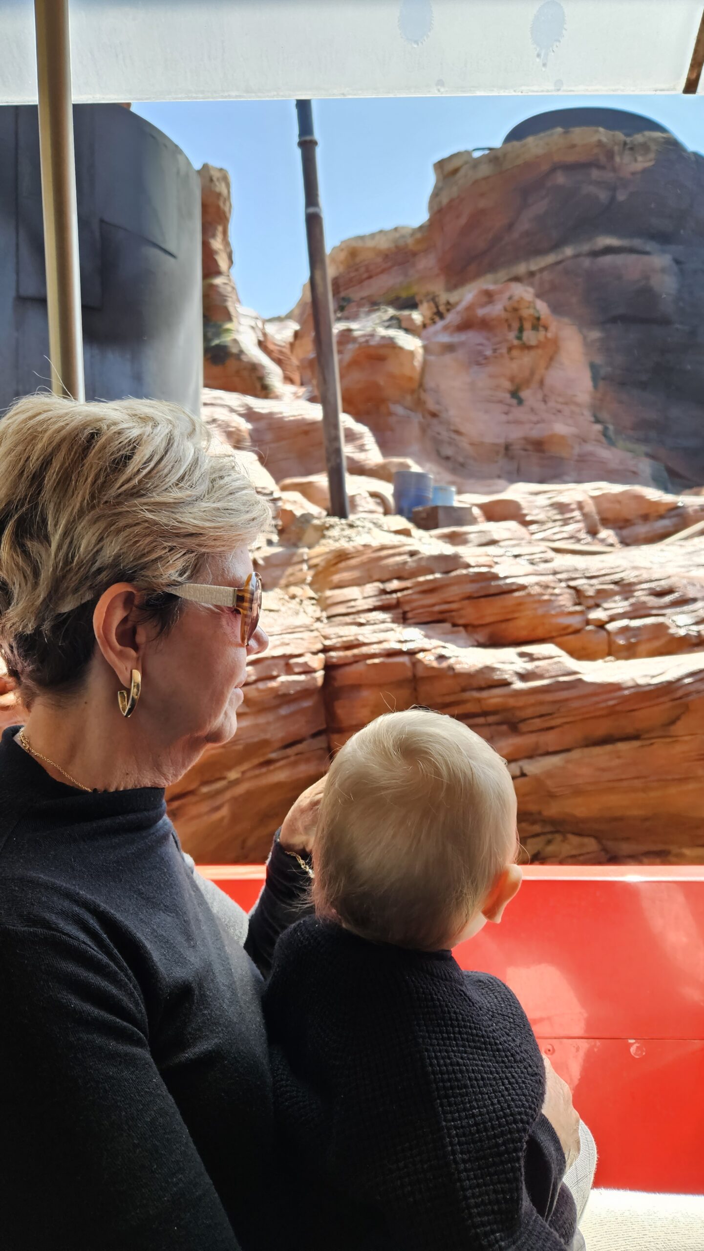Avo com o bebe no colo em frente as formacoes rochosas da atracao Big Thunder Mountain na Disneyland Paris