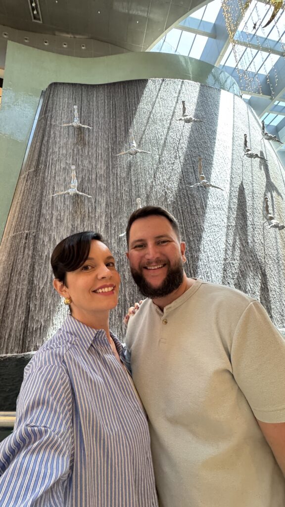 Casal em frente à cachoeira dos mergulhadores no Dubai Mall