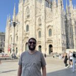 Fachada do Duomo di Milano em mármore claro, fotografada de um ângulo próximo à entrada