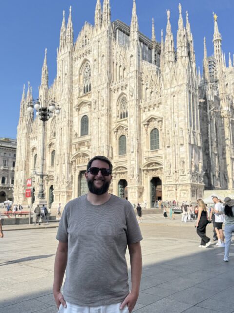 Fachada do Duomo di Milano em mármore claro, fotografada de um ângulo próximo à entrada