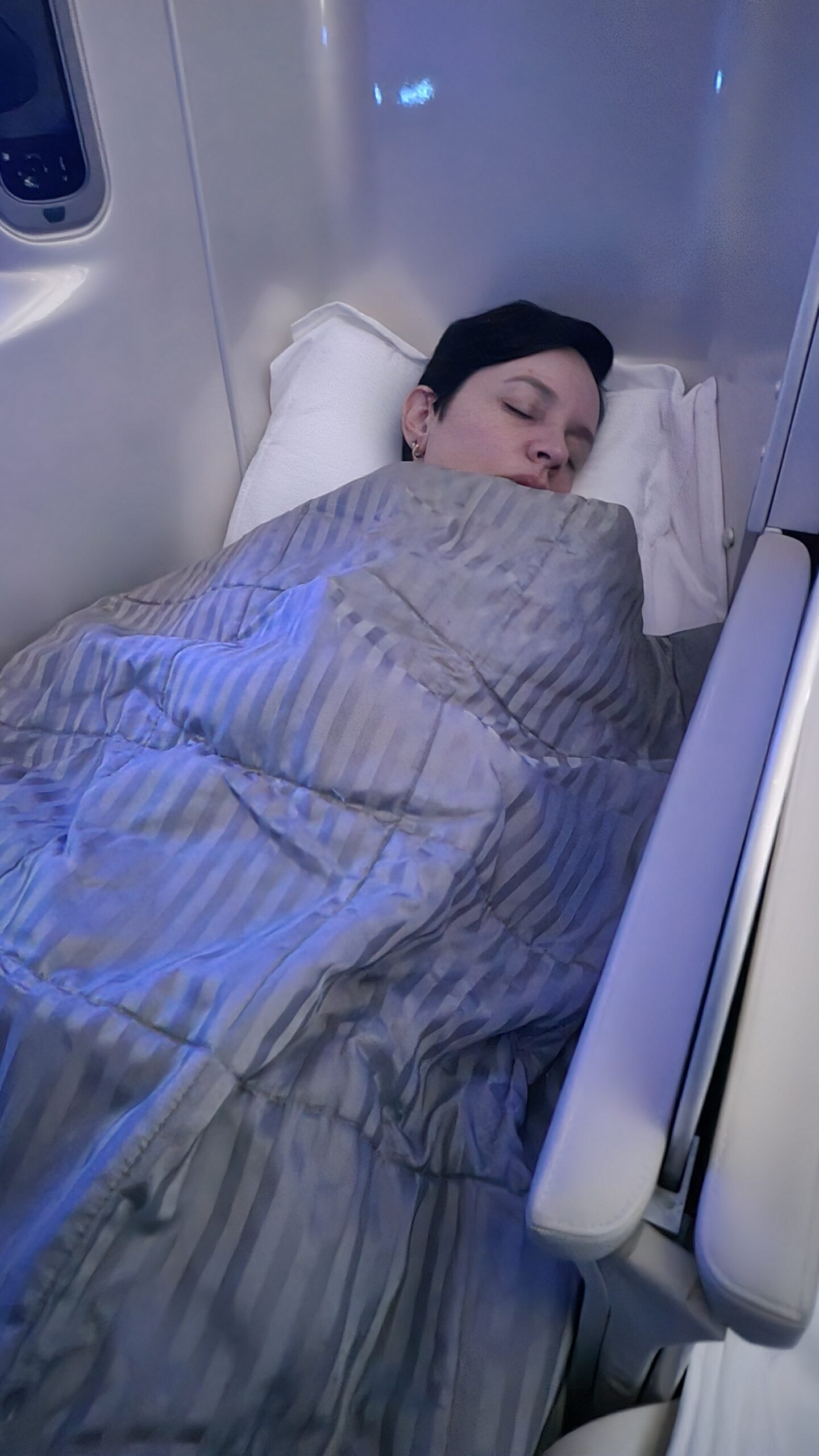Carol dormindo na cama plana da executiva do A380 da Emirates