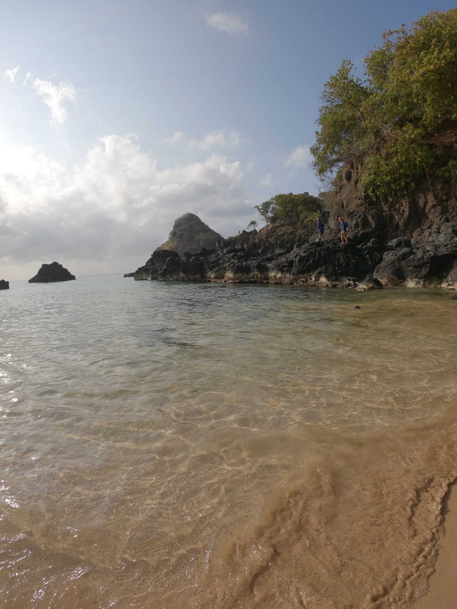 Enseada de Fernando de Noronha com falésias, água transparente e areia clara