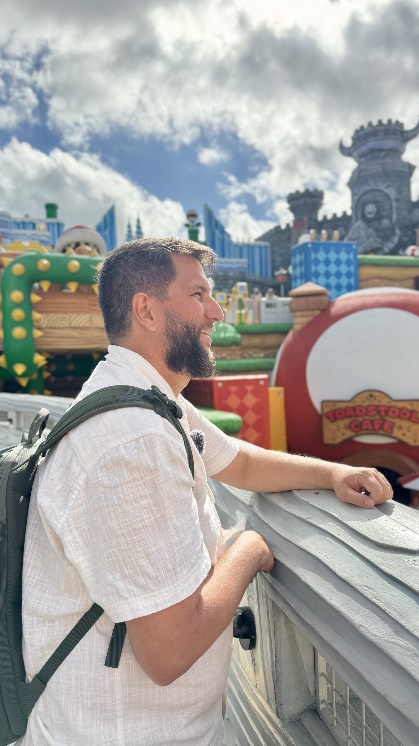 Visitante observando a area do Super Nintendo World de uma passarela, com o Toadstool Cafe e o castelo ao fundo